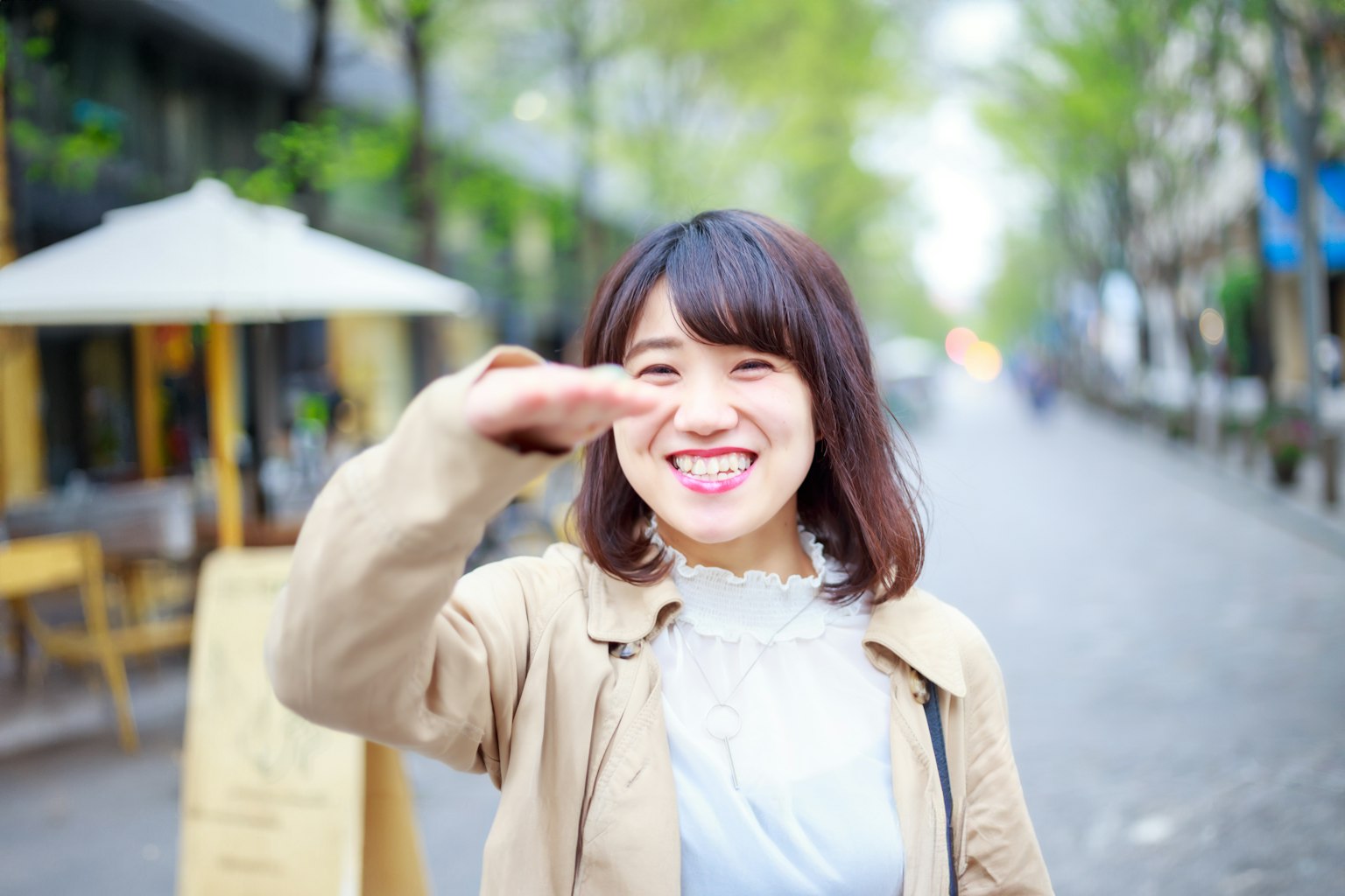 一位女性在街道上微笑並揮手