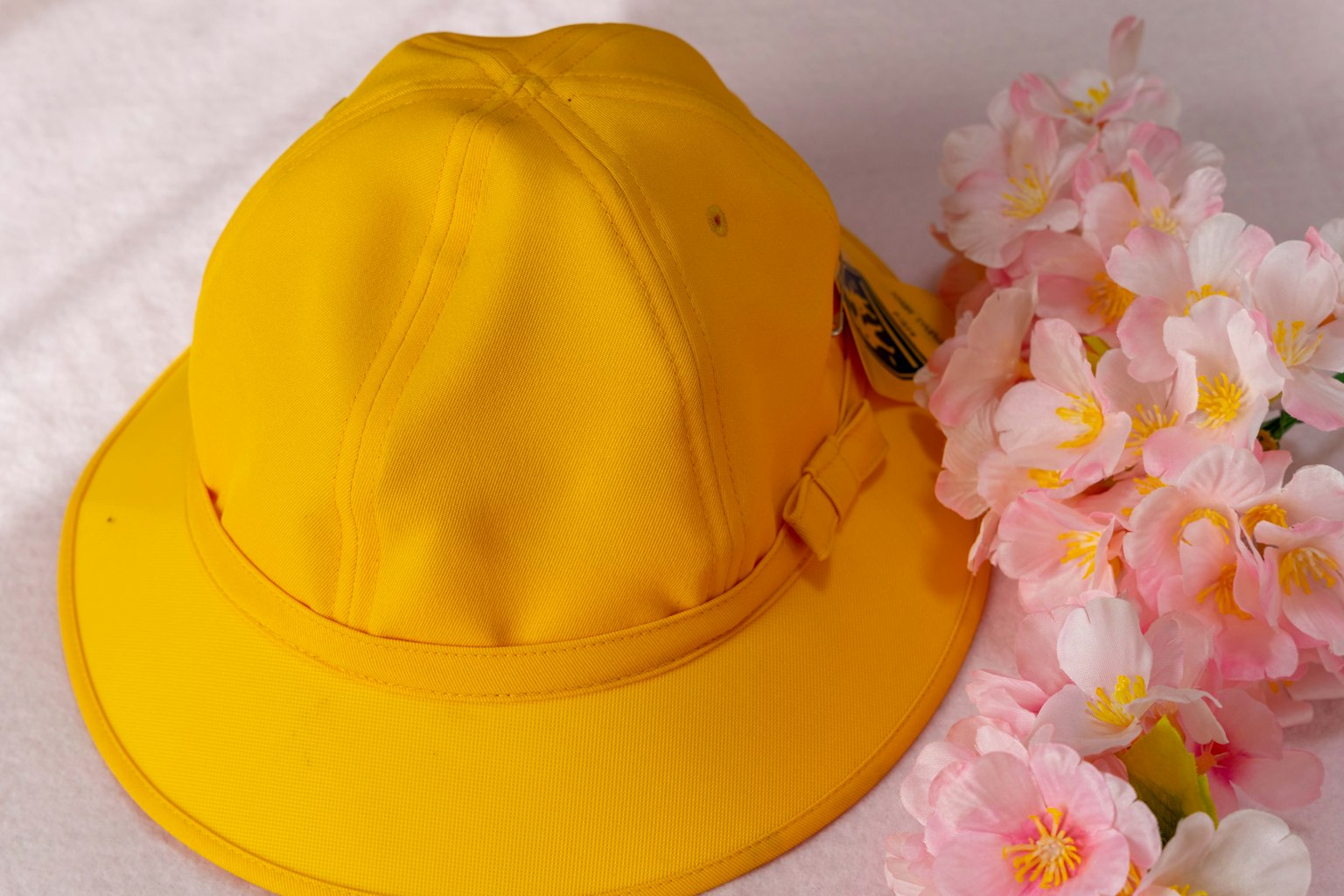 Topi kuning di samping bunga pink