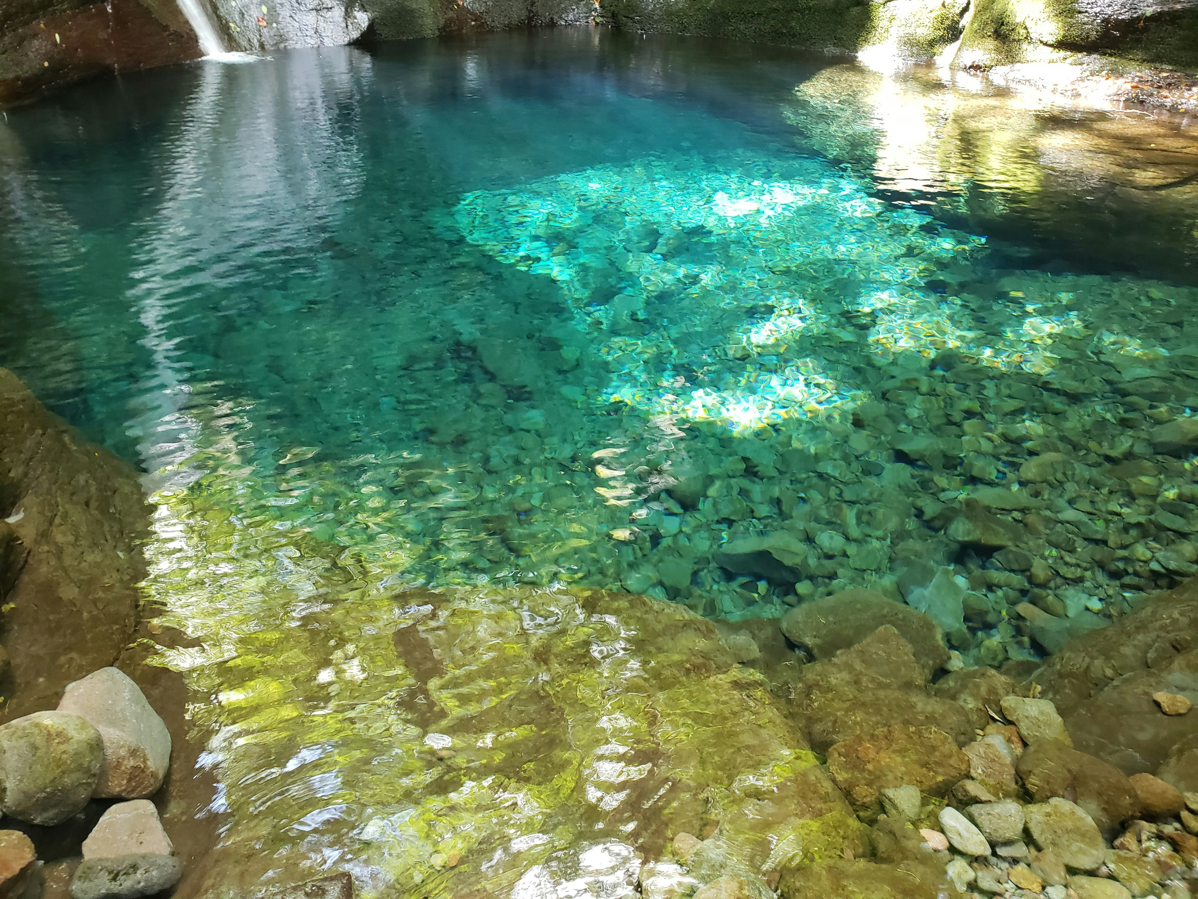 澄んだ滝壺の水面と岩の流れ