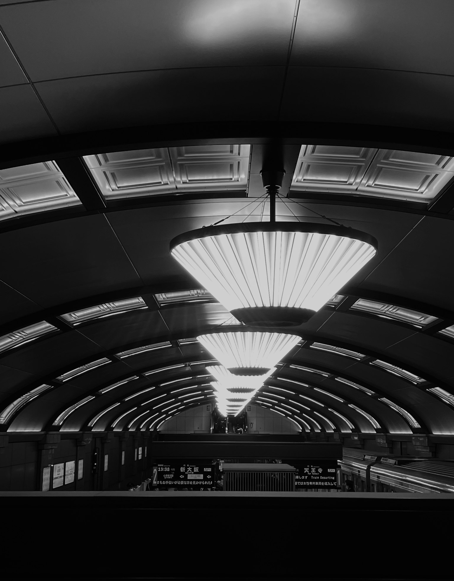 Einzigartiges Lichtdesign an der Decke eines schwarz-weißen Bahnhofs