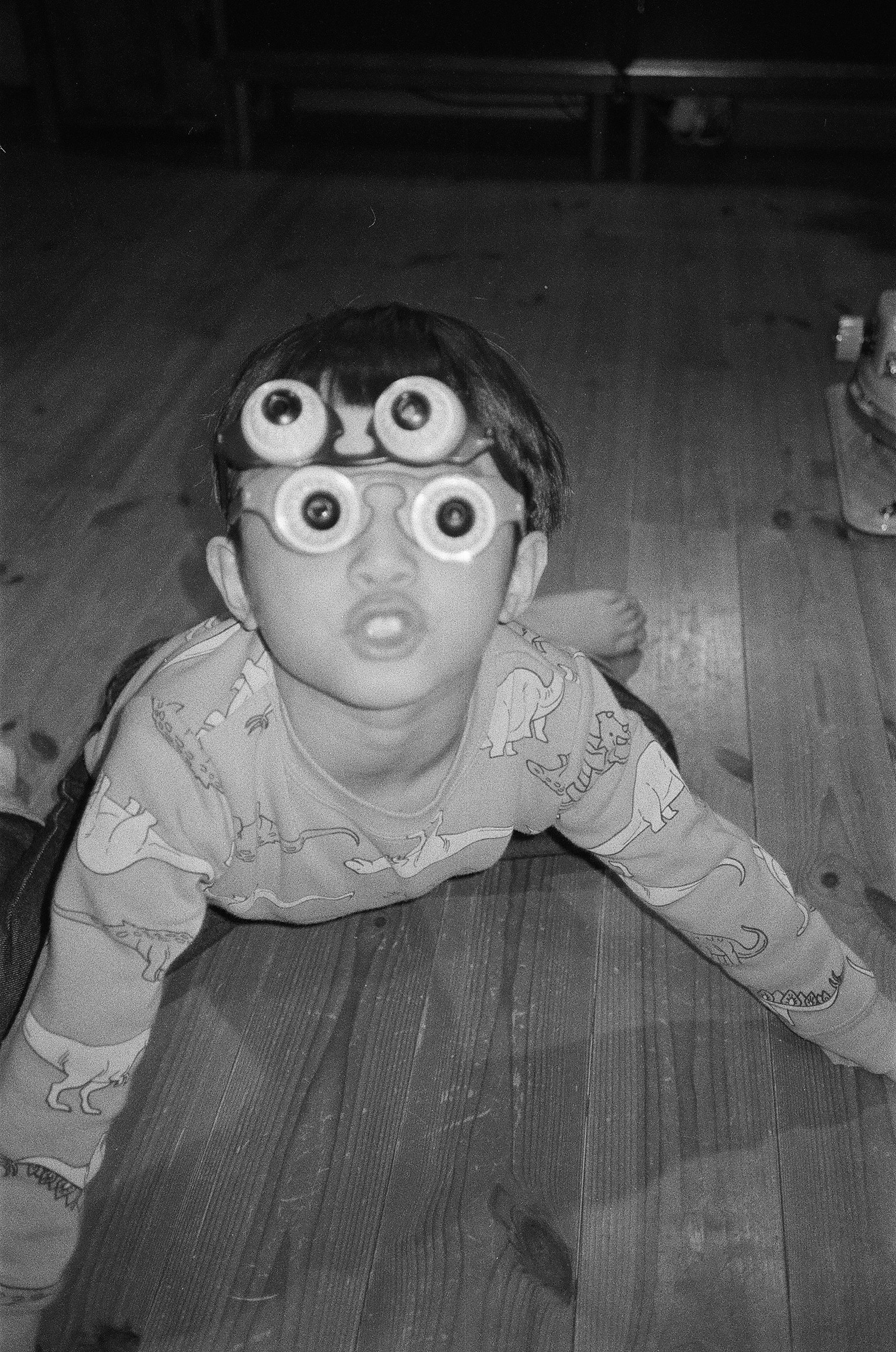 孩子額頭上有玩具眼睛，正在木地板上爬行
