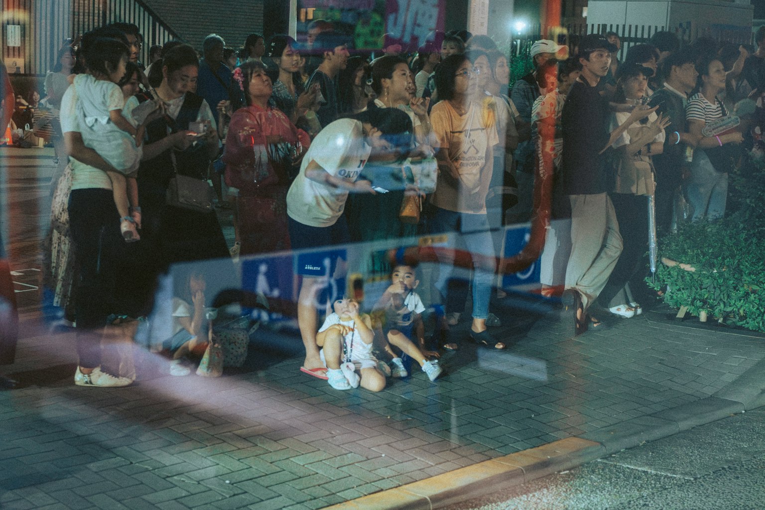 Familias y niños reunidos en una calle concurrida durante un festival nocturno