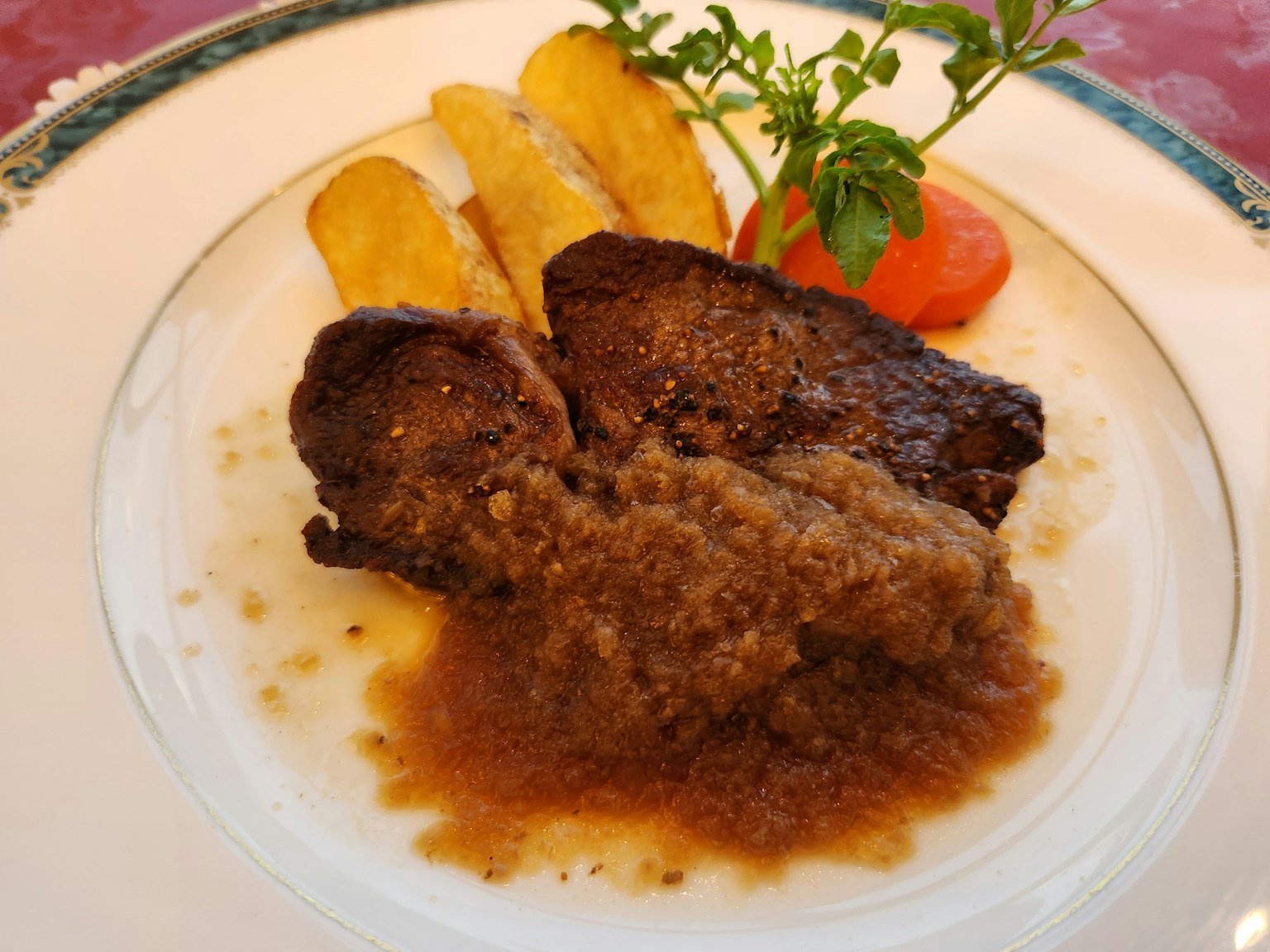 Piatto di carne con salsa accompagnato da platano fritto e pomodoro