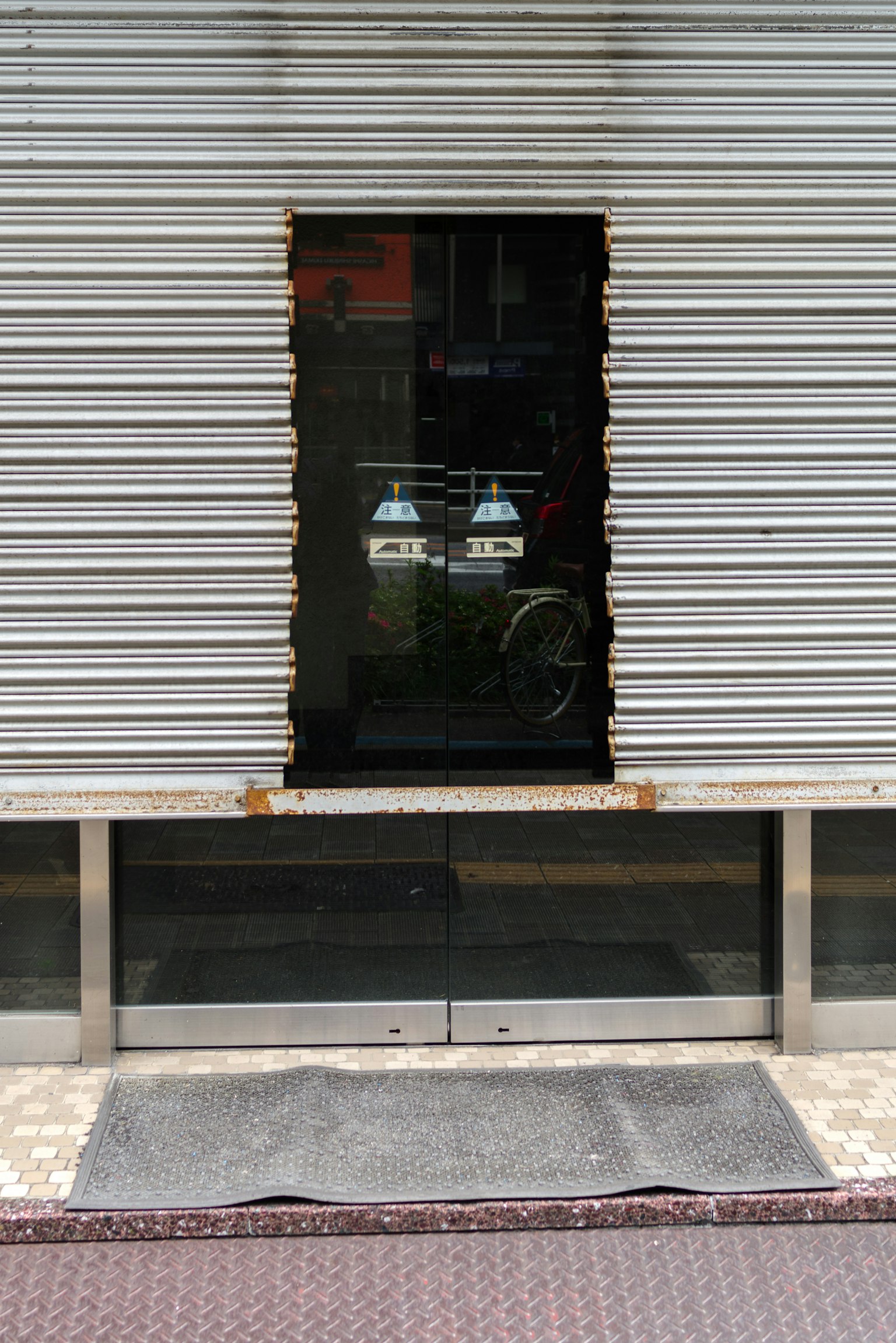 Fenêtre noire sur une vitrine avec un rideau métallique fermé