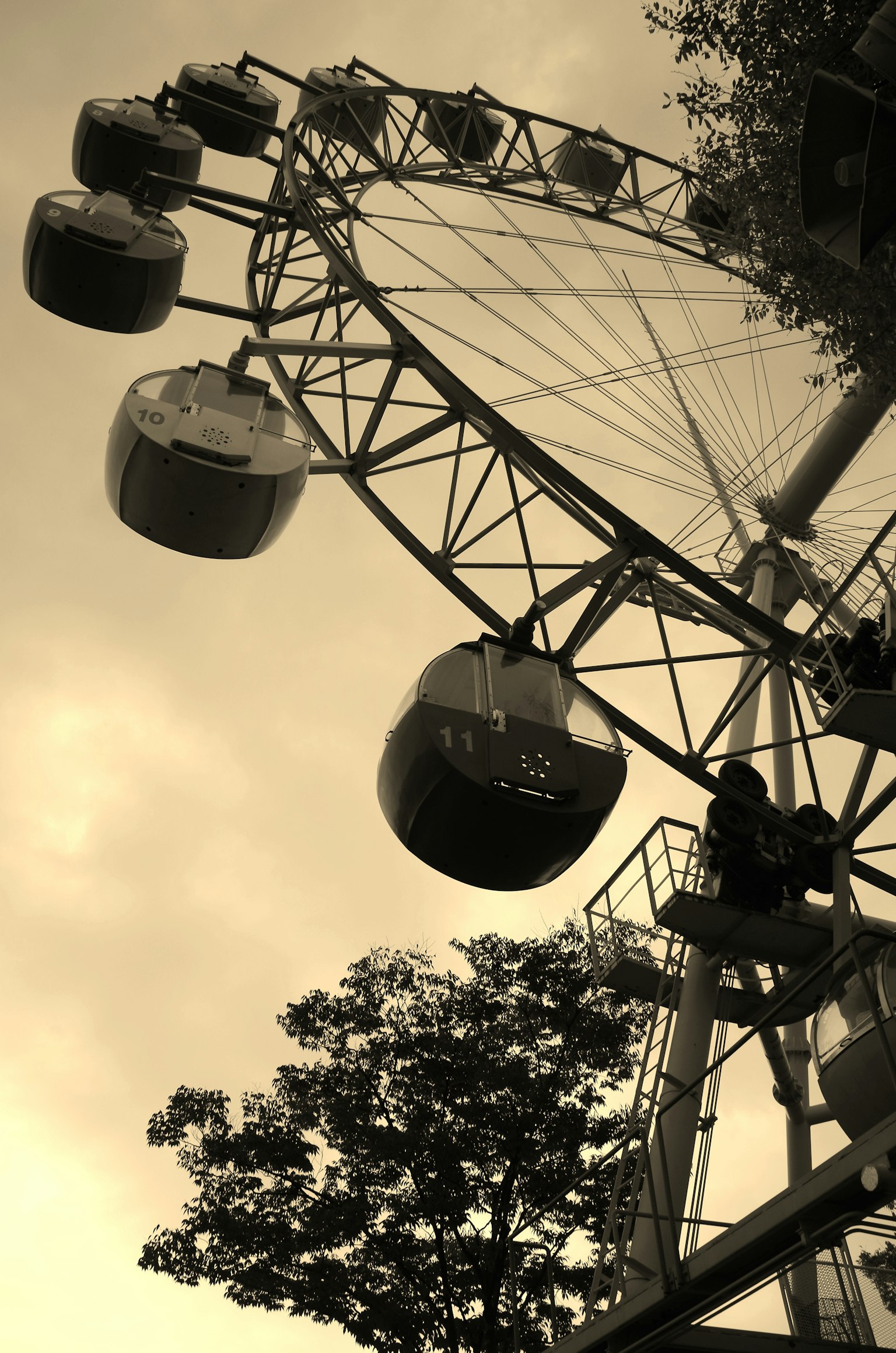 Grande roue capturée d'un angle bas avec des tons sépia et des cabines alignées