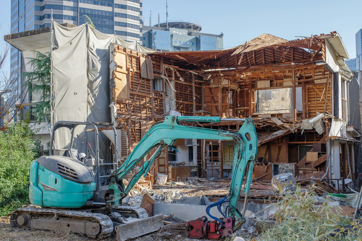 施工现场，绿色挖掘机和部分拆除的建筑