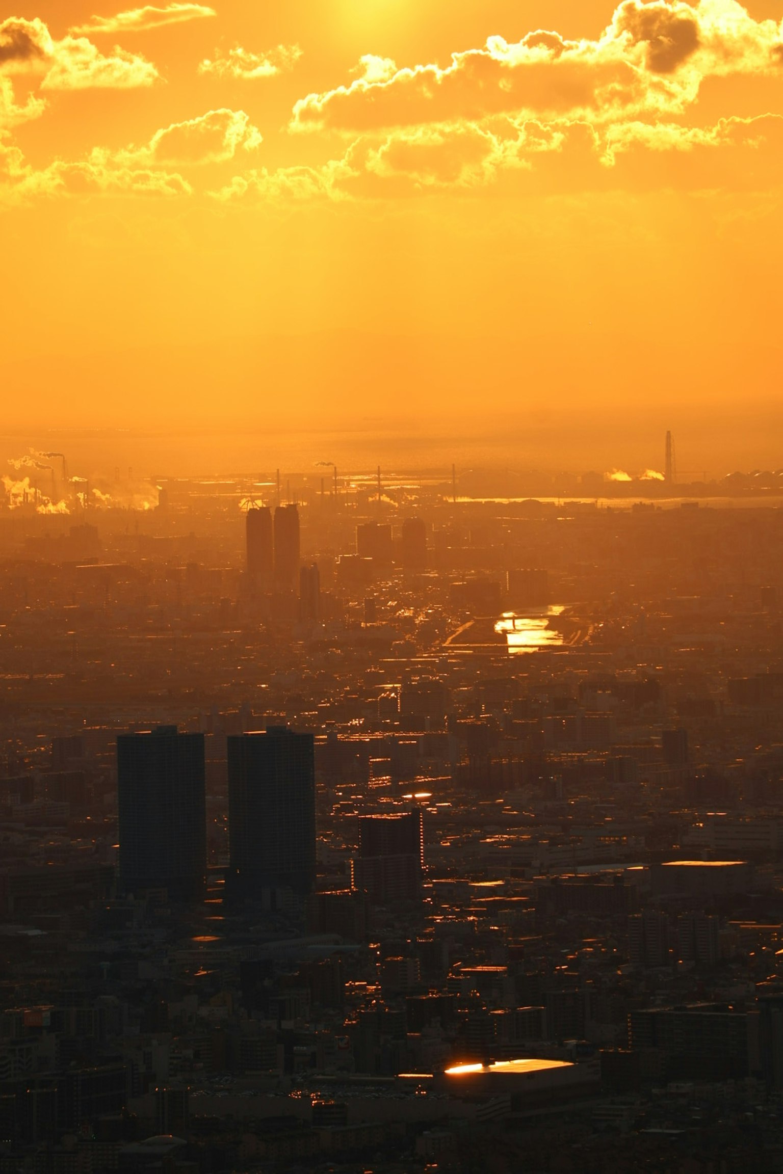Cityscape bathed in orange sunset light featuring skyscrapers and a river