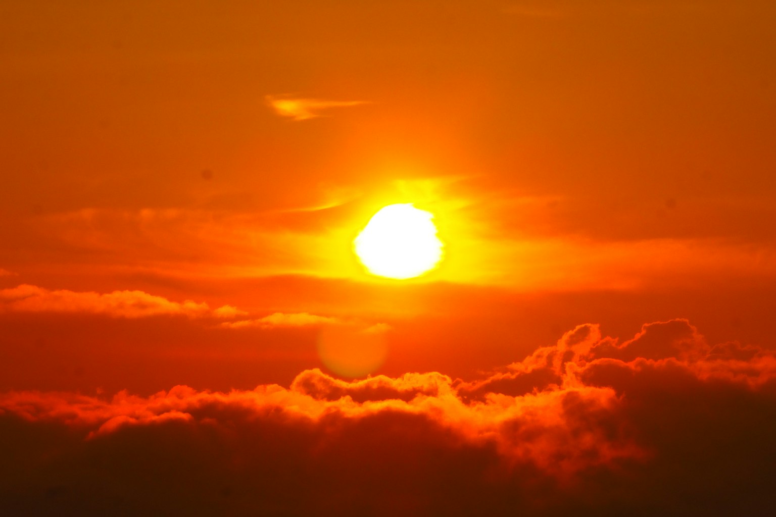Langit senja dengan matahari yang cerah dan siluet awan
