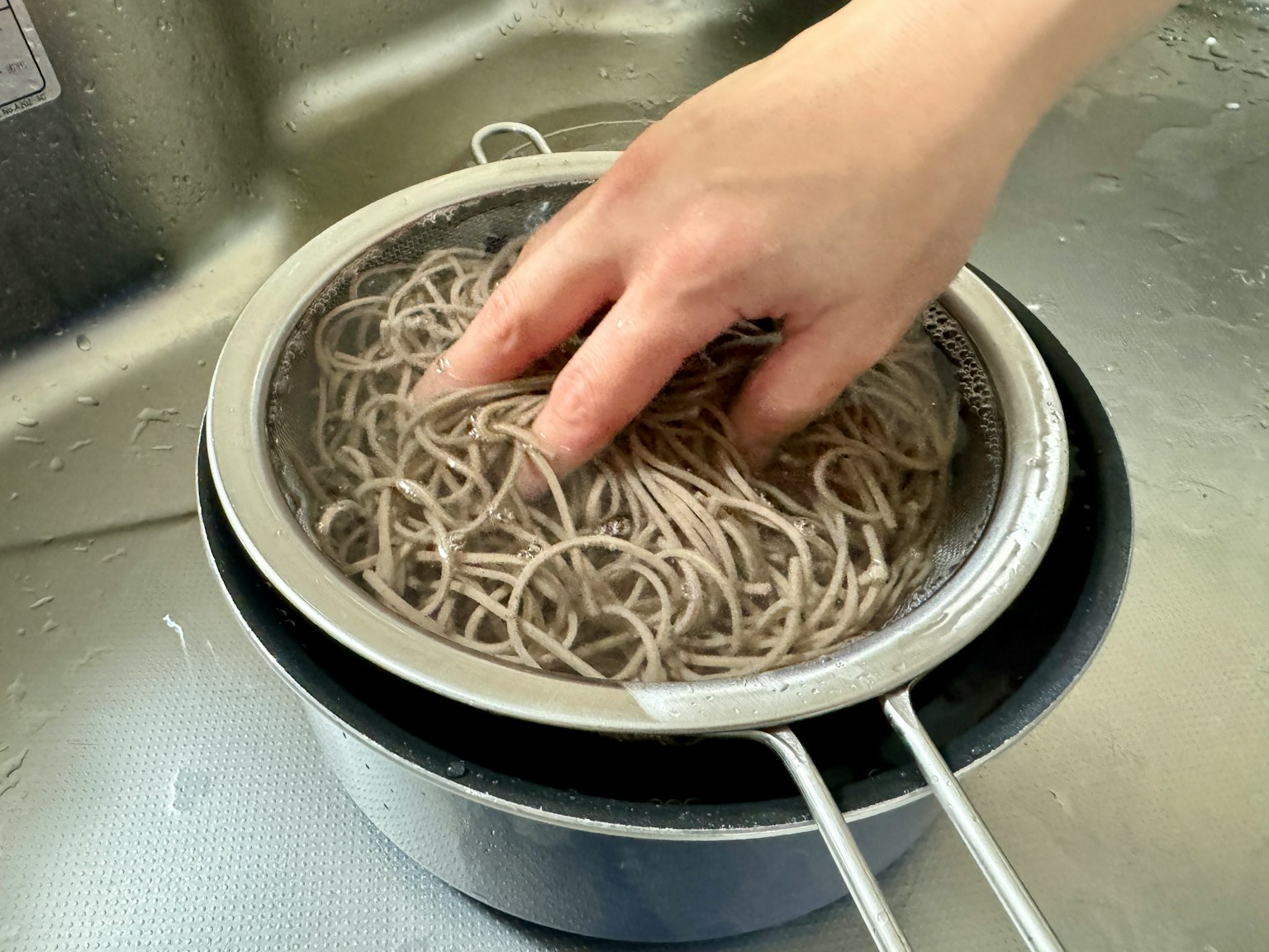 มือกำลังกรองบะหมี่โซบะในกระชอน