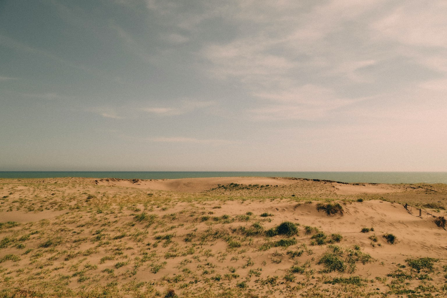 Expansive sand dunes with a calm sea view