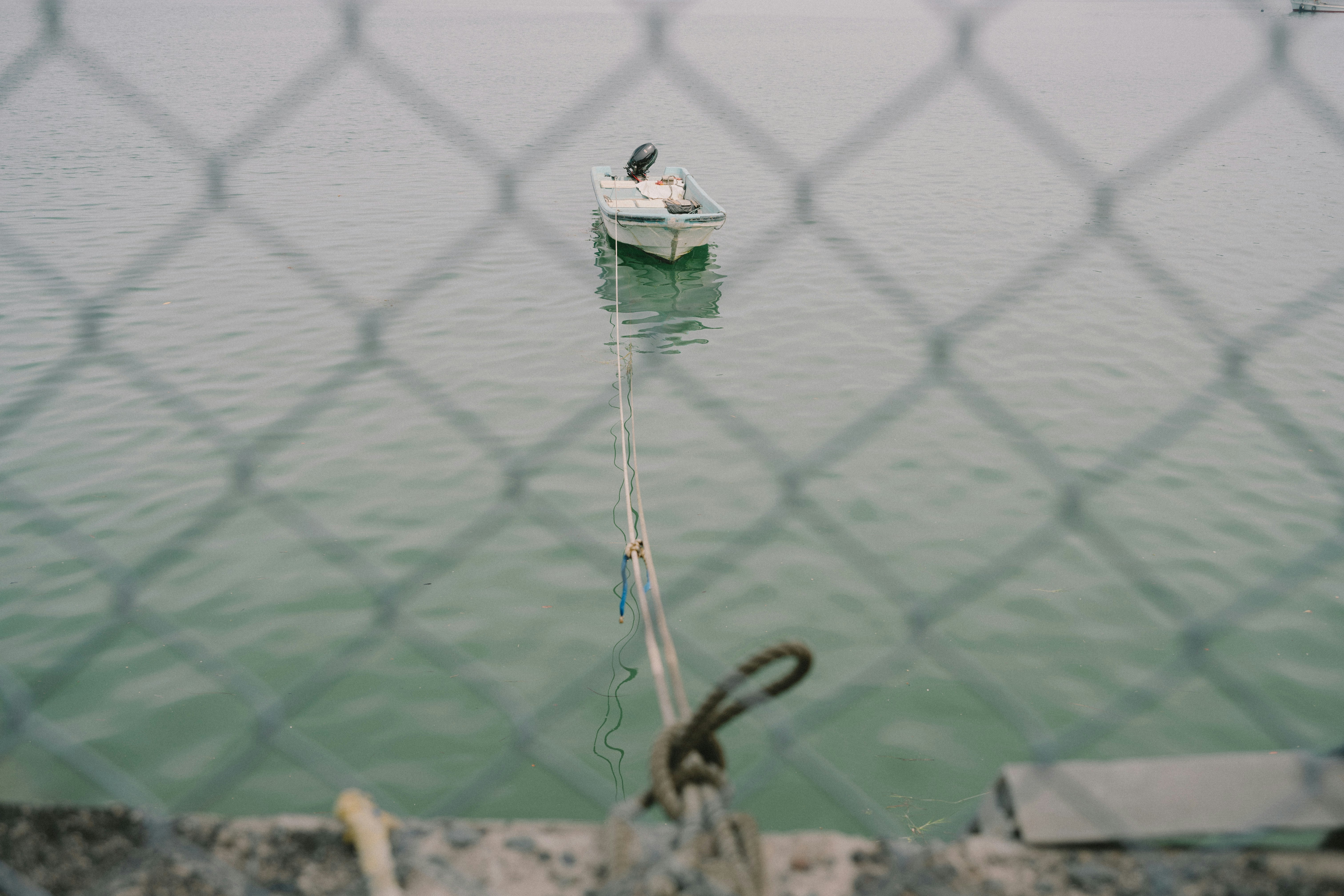 small boat floating on the water seen through a net image