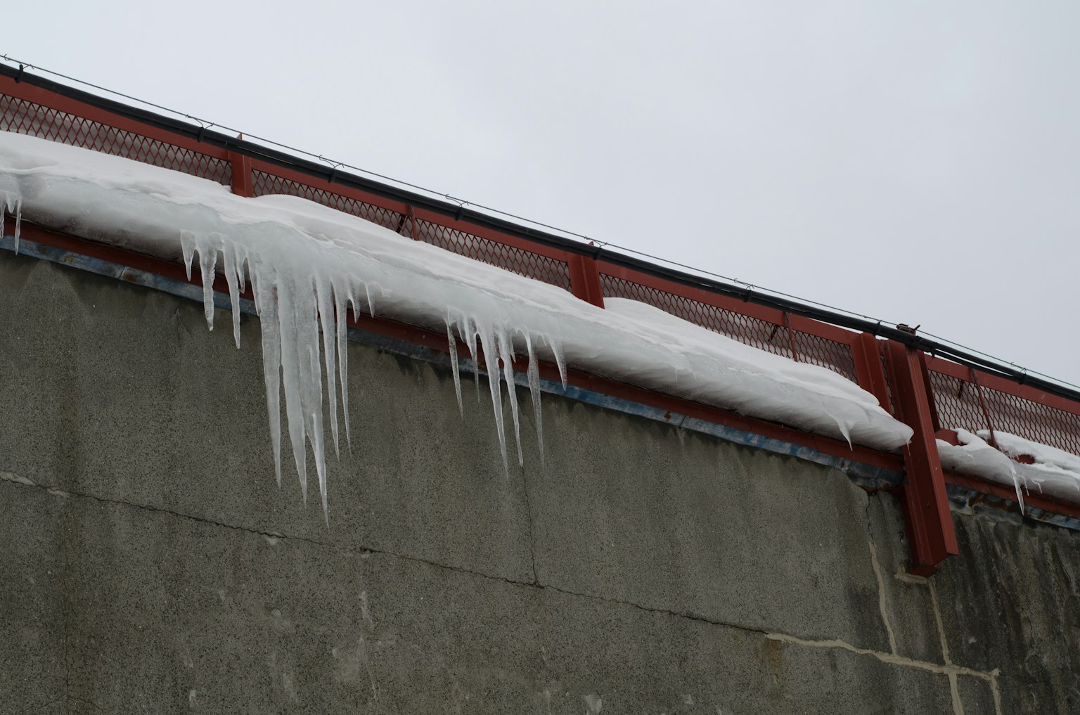 Gambar icicle dan salju di tepi atap dinding beton