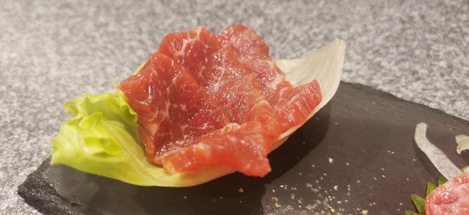 Daging mentah segar diletakkan di atas daun selada