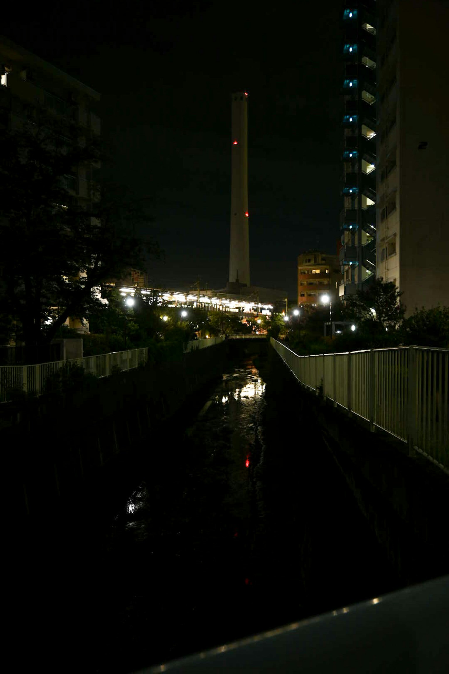 夜間城市景觀，包含煙囪和亮燈建築
