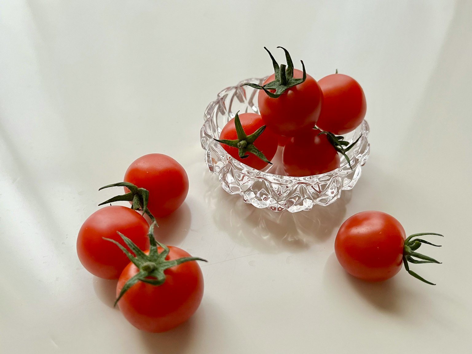 투명한 그릇에 담긴 신선한 토마토와 주변에 흩어진 토마토