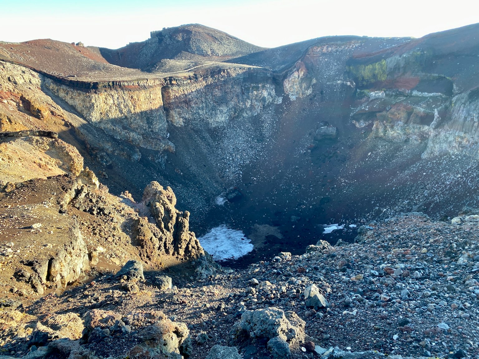 Blick auf einen Vulkankrater mit felsigem Gelände und Eis
