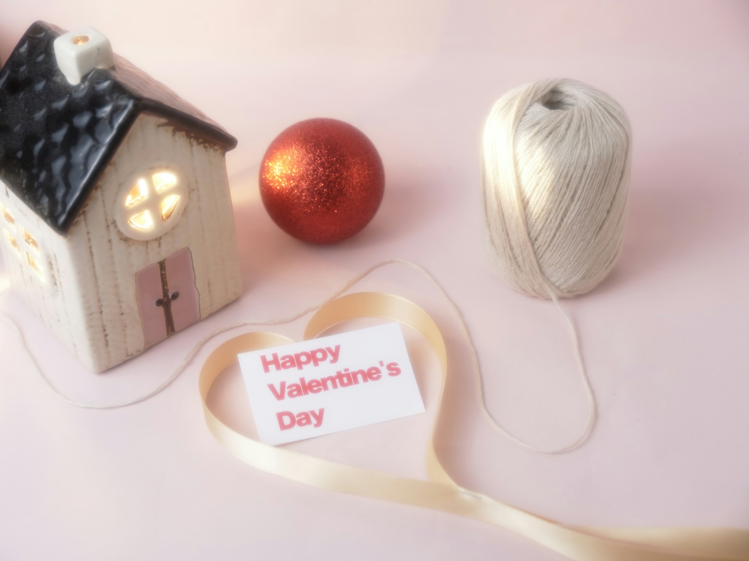 A small house, a red ball, and a spool of thread with a Valentine's Day message