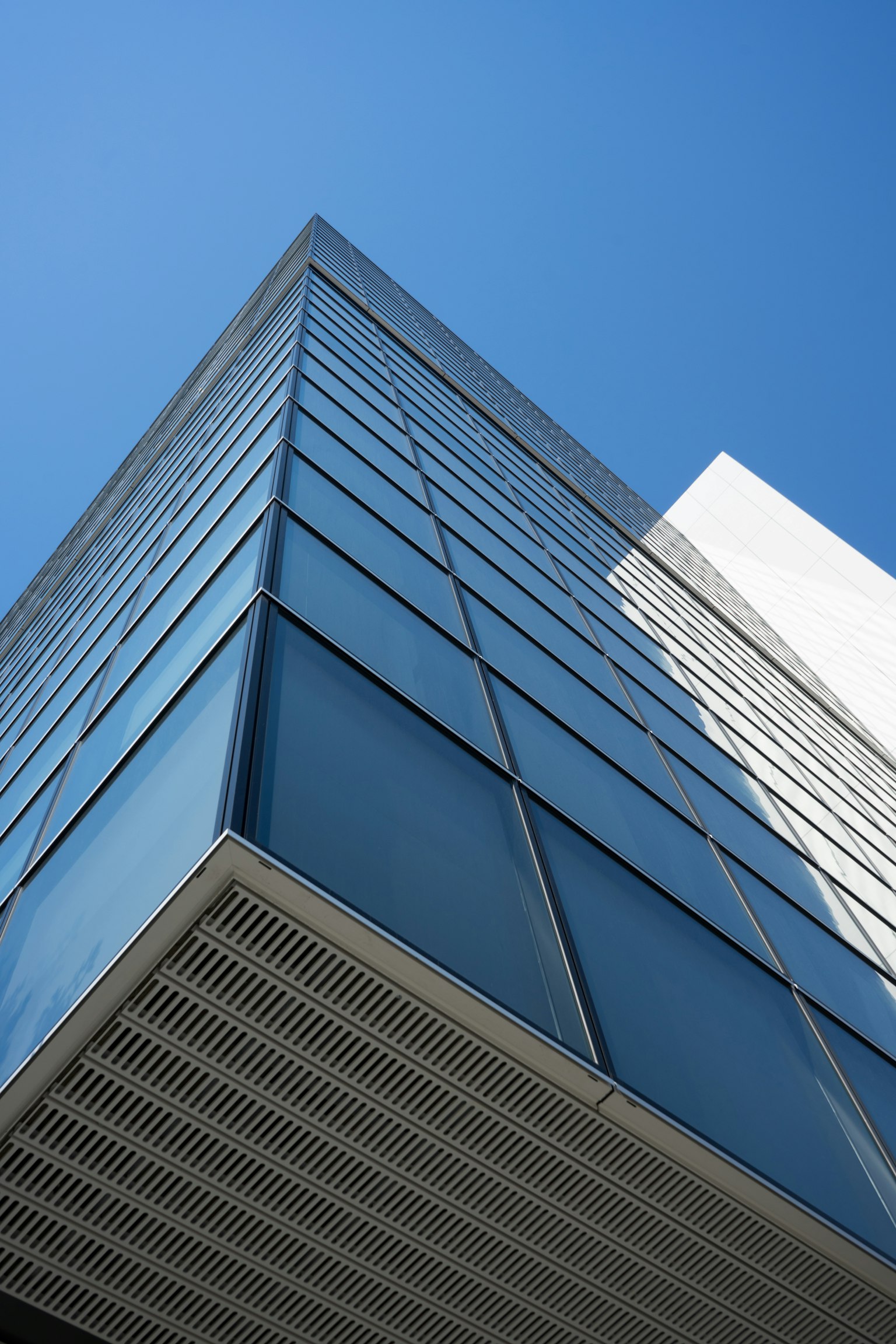 Vue d'un bâtiment moderne en verre depuis un angle bas sous un ciel bleu