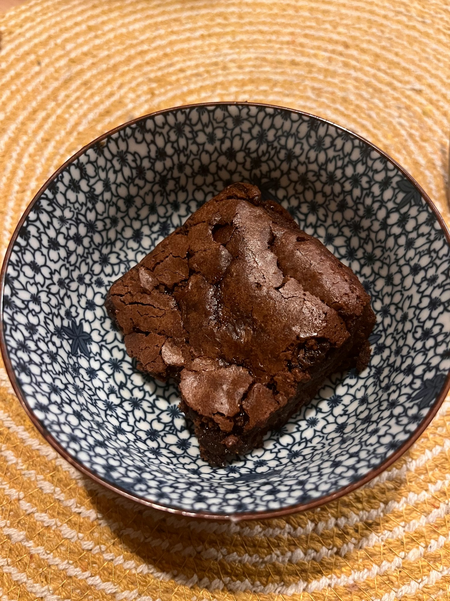 Un trozo de brownie servido en un tazón con patrón azul