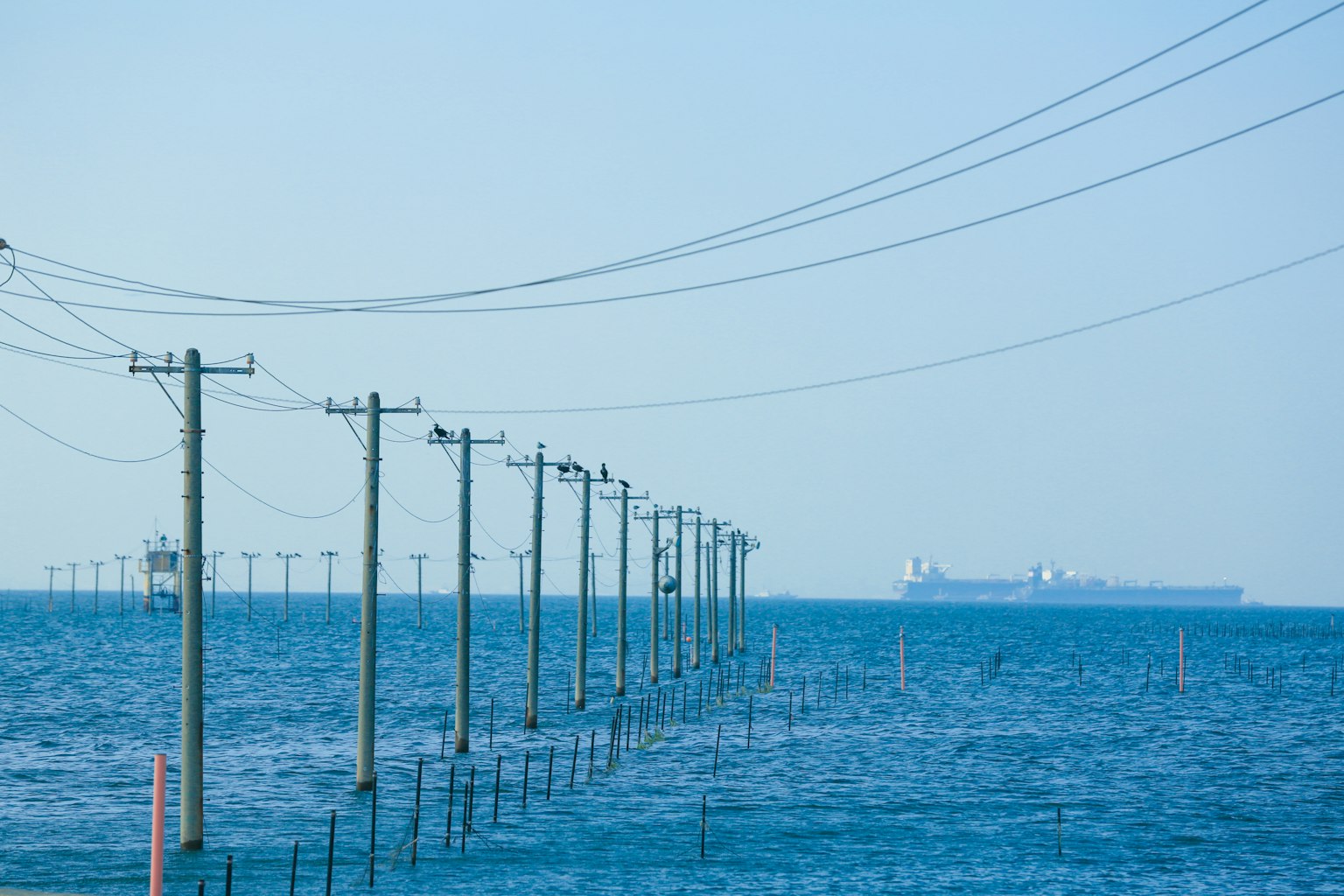 View of utility poles and power lines over the ocean