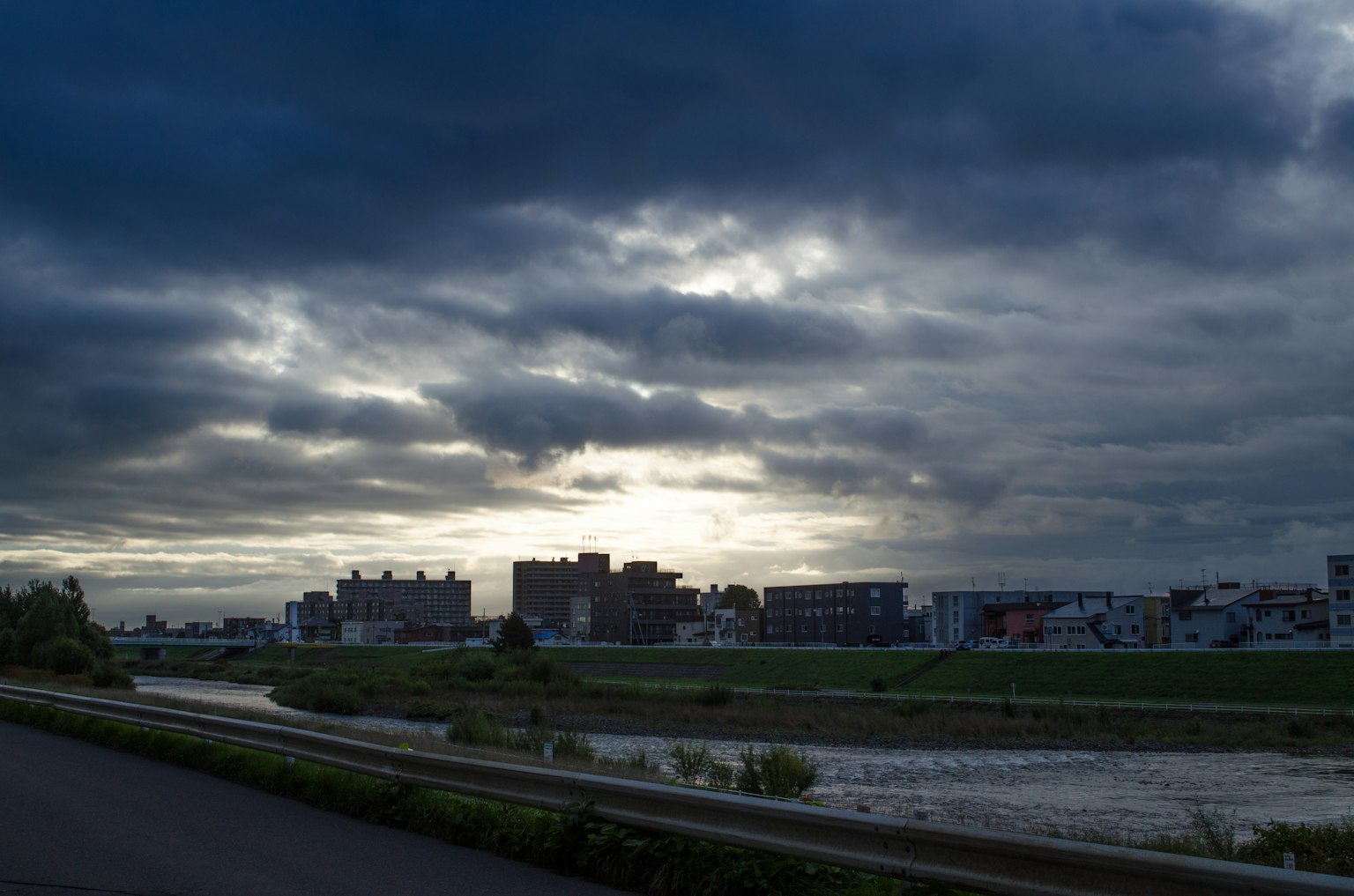 Nuages sombres sur un paysage de rivière avec des bâtiments visibles