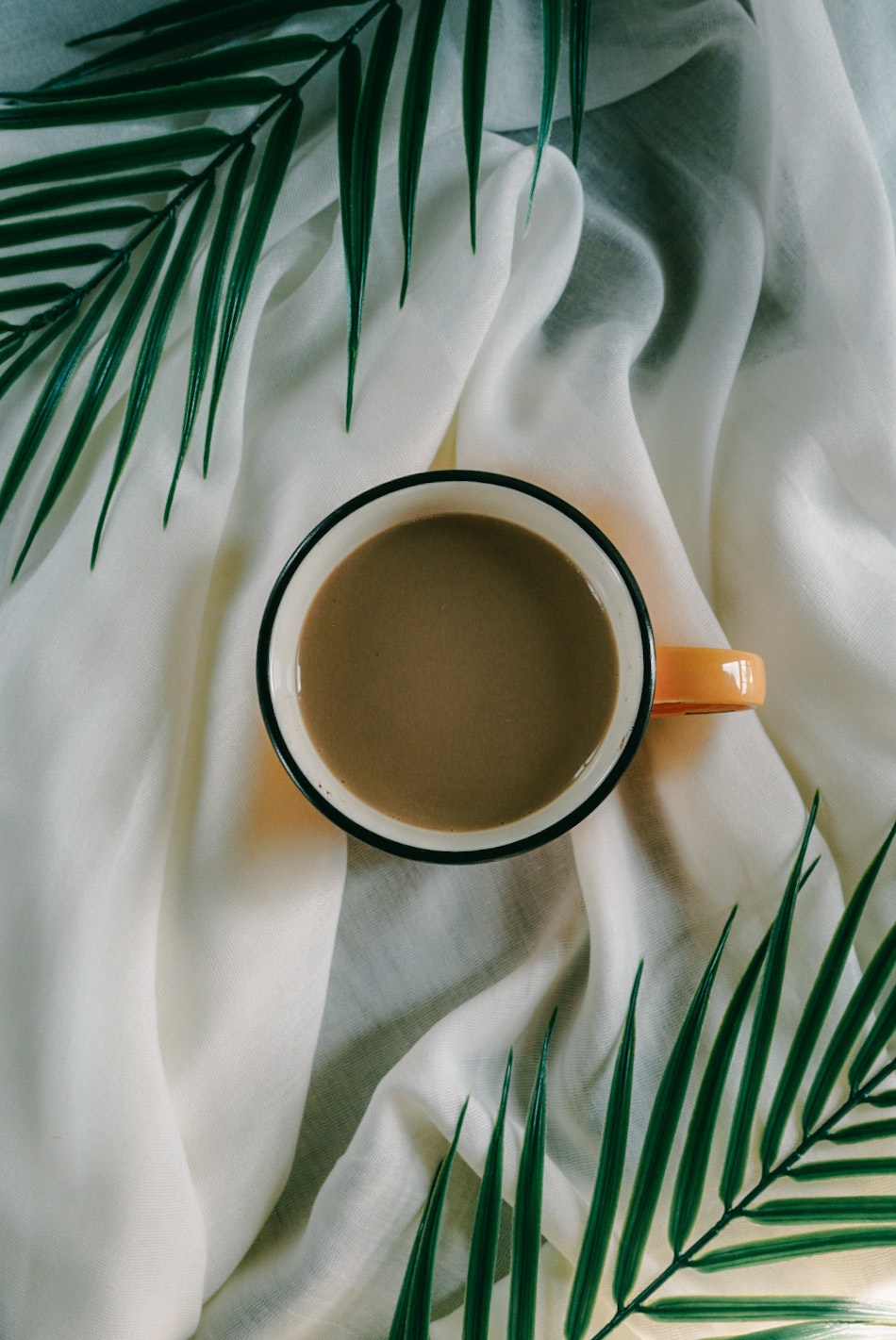 Top-down view of a coffee cup on leafy fabric