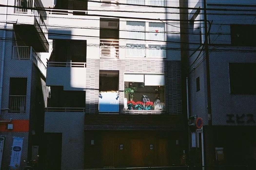 Blick in eine enge Gasse mit Gebäudefenstern und oberirdischen Kabeln