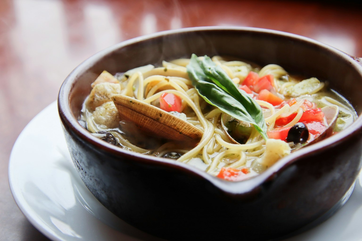 Bowl of soup with pasta topped with fresh tomatoes and basil