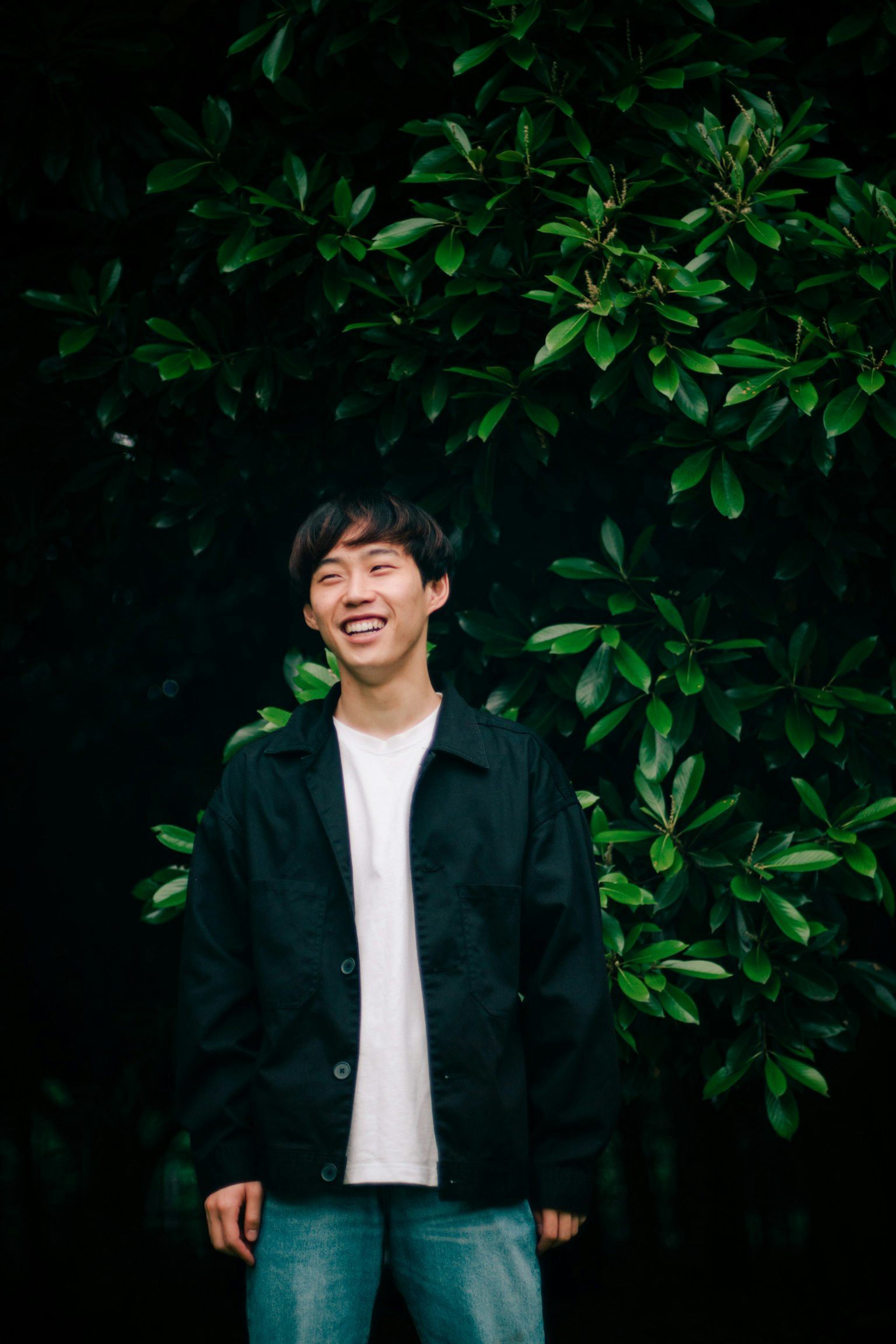 녹색 잎을 배경으로 서 있는 웃고 있는 남자