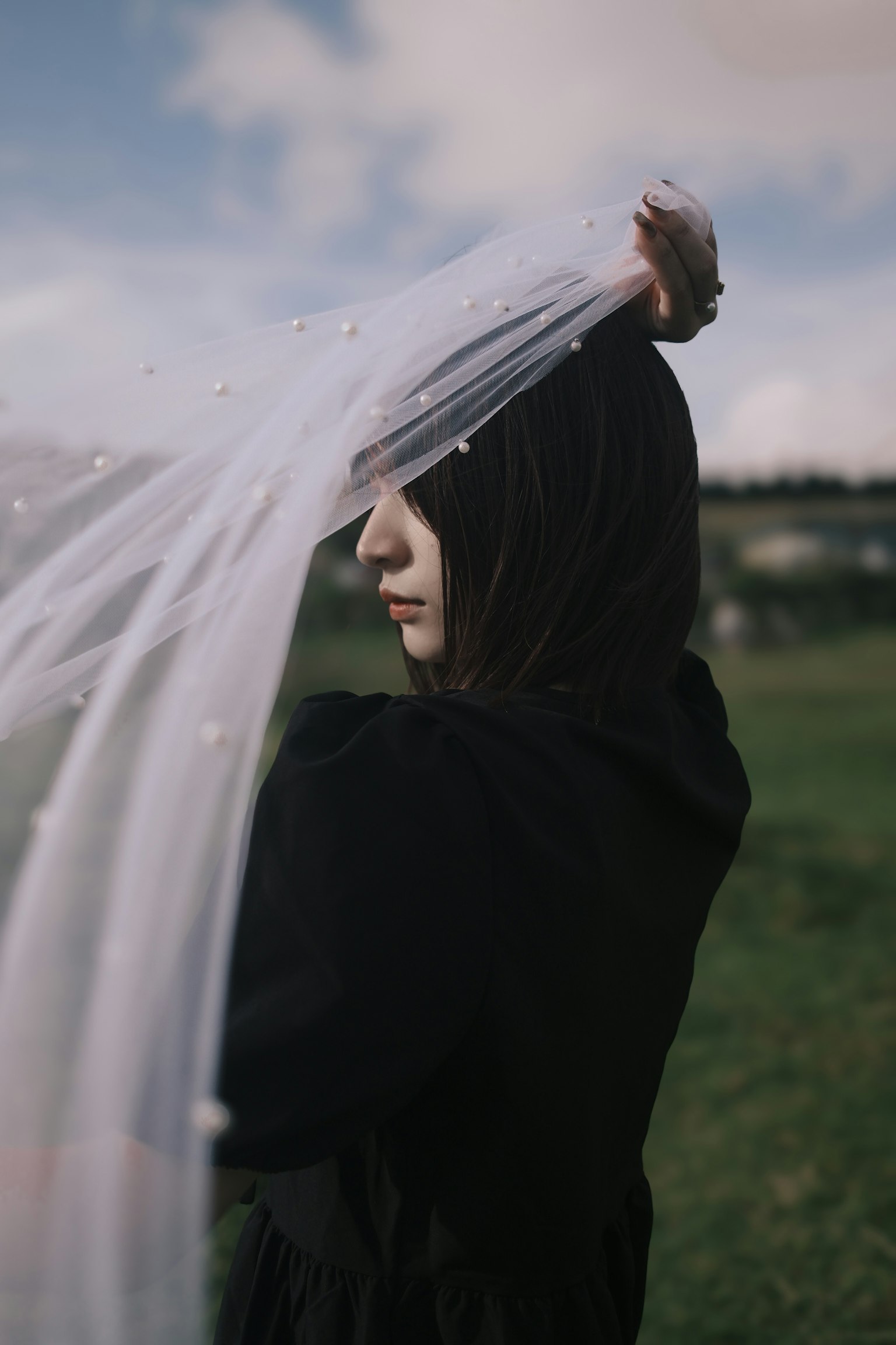 黒い服を着た女性が透明な布を持っている風景