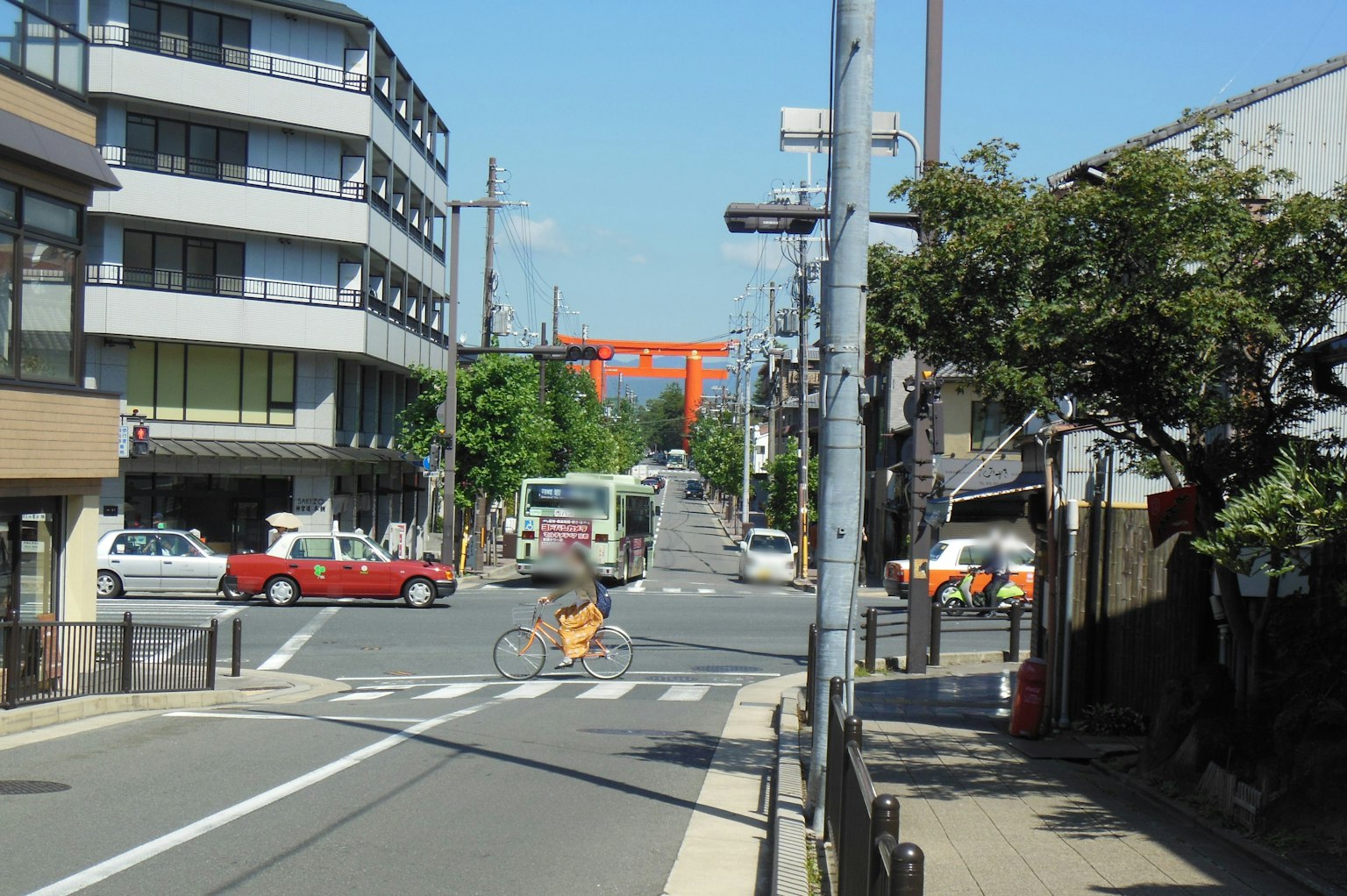 Street intersection featuring a red torii gate with a cyclist