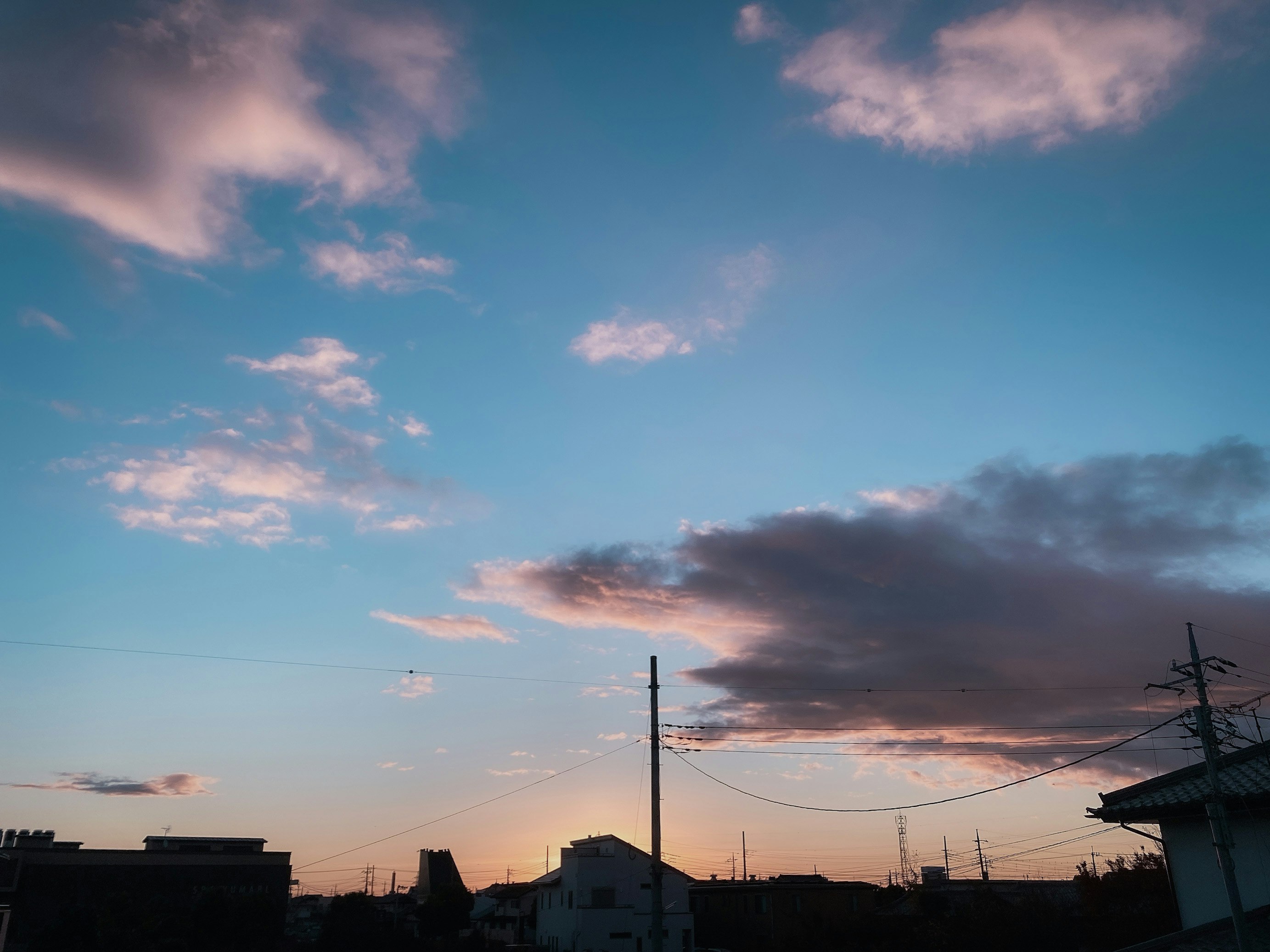 cielo de atardecer con nubes y cables eléctricos sobre el paisaje urbano