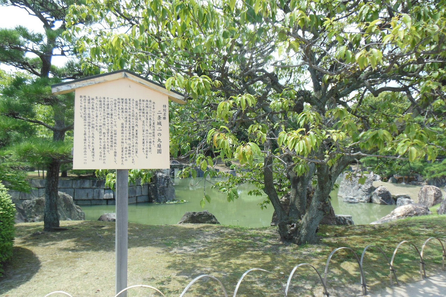 靠近池塘的信息牌与郁郁葱葱的树木