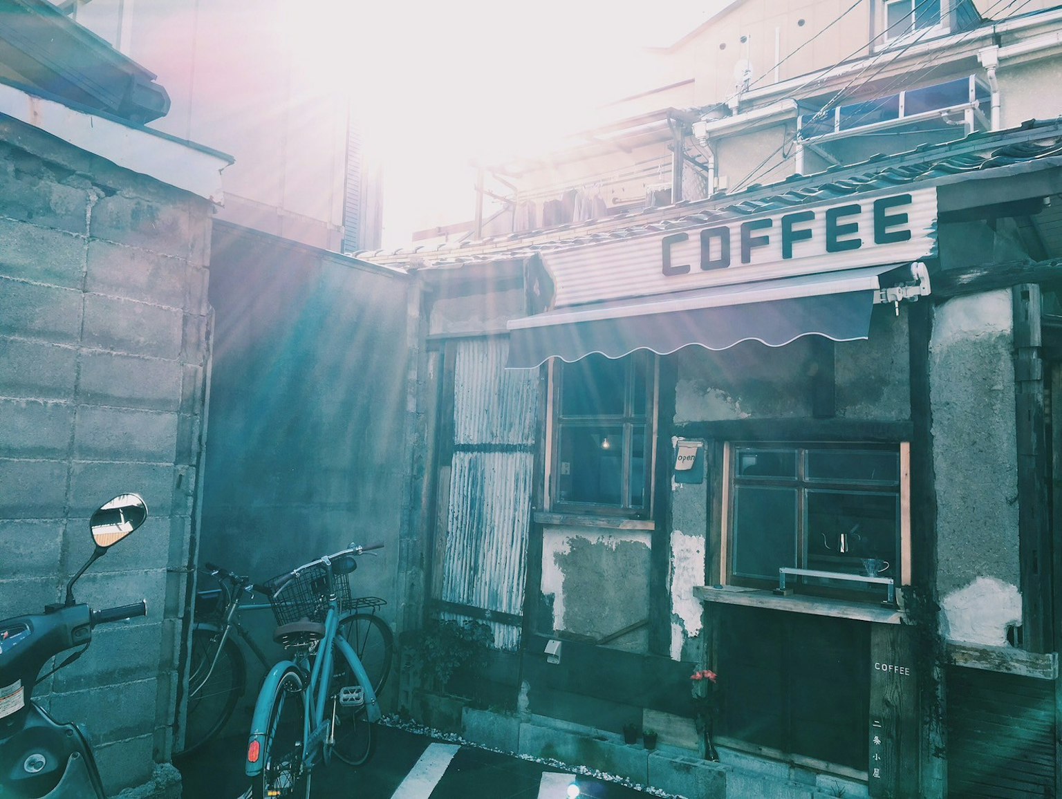 旧咖啡店的外观，阳光明媚下有一辆自行车