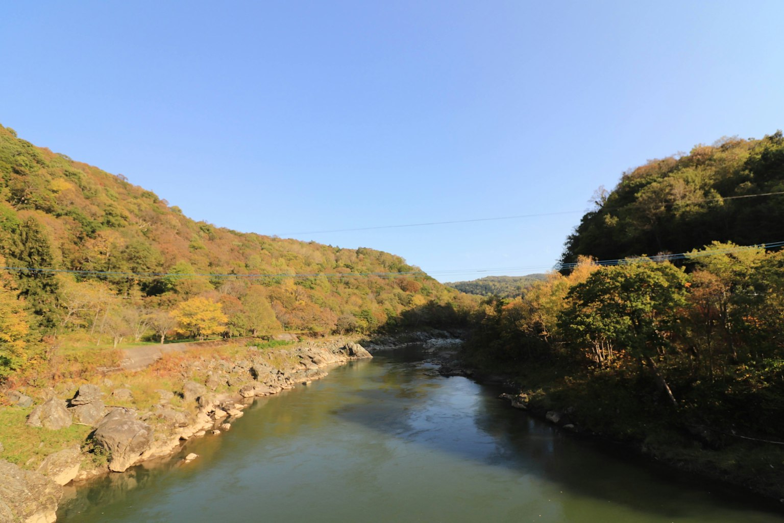 Vue pittoresque d'une rivière tranquille entourée de feuillage d'automne et de collines