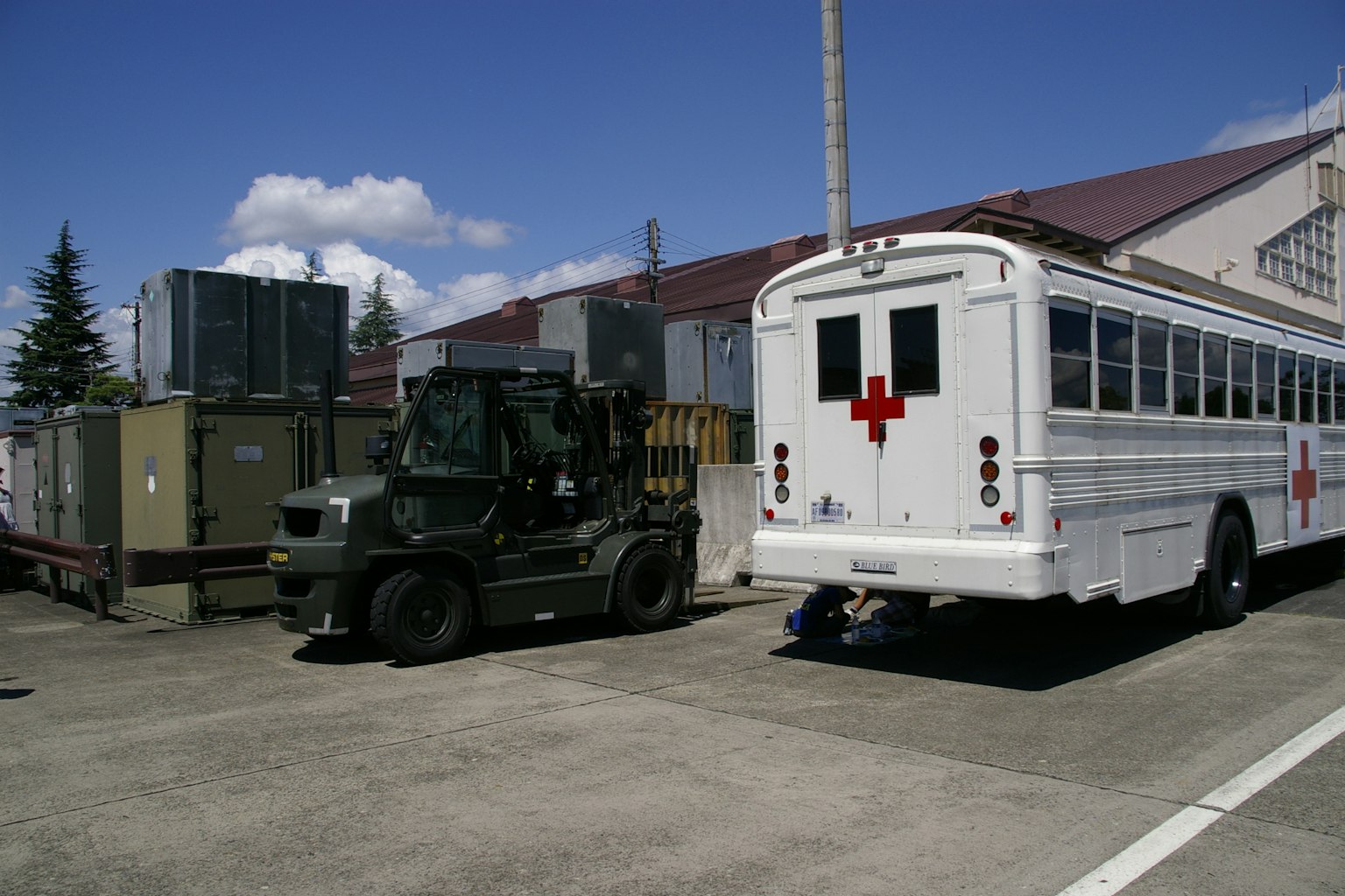 Un autobús ambulancia blanco y un vehículo militar estacionados al aire libre