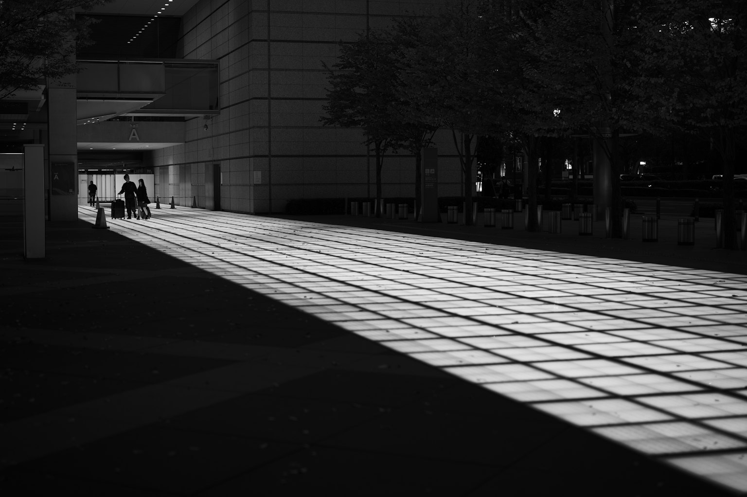Black and white urban landscape with illuminated walkway people walking