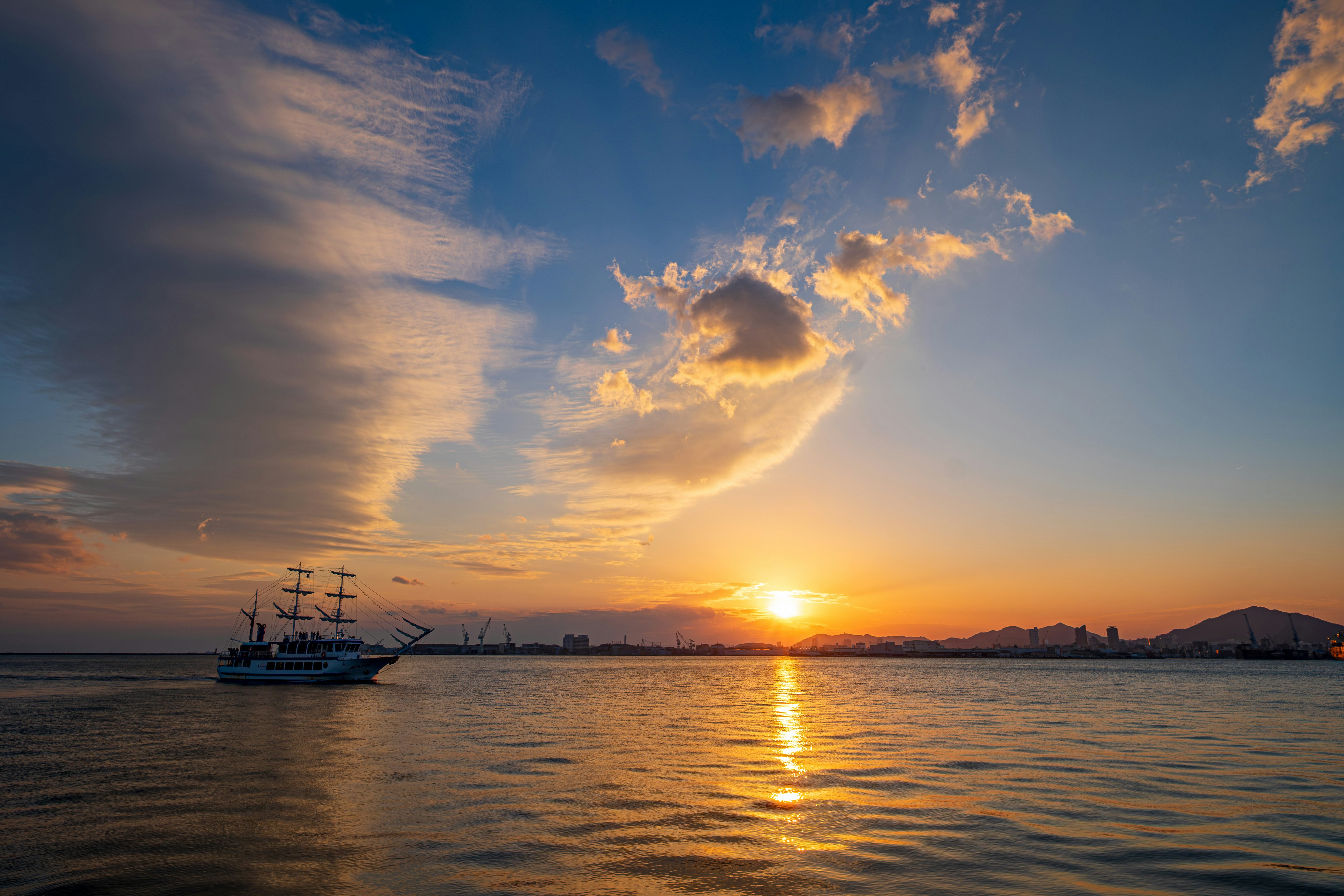 神戸港の海上を行く観光船と夕日