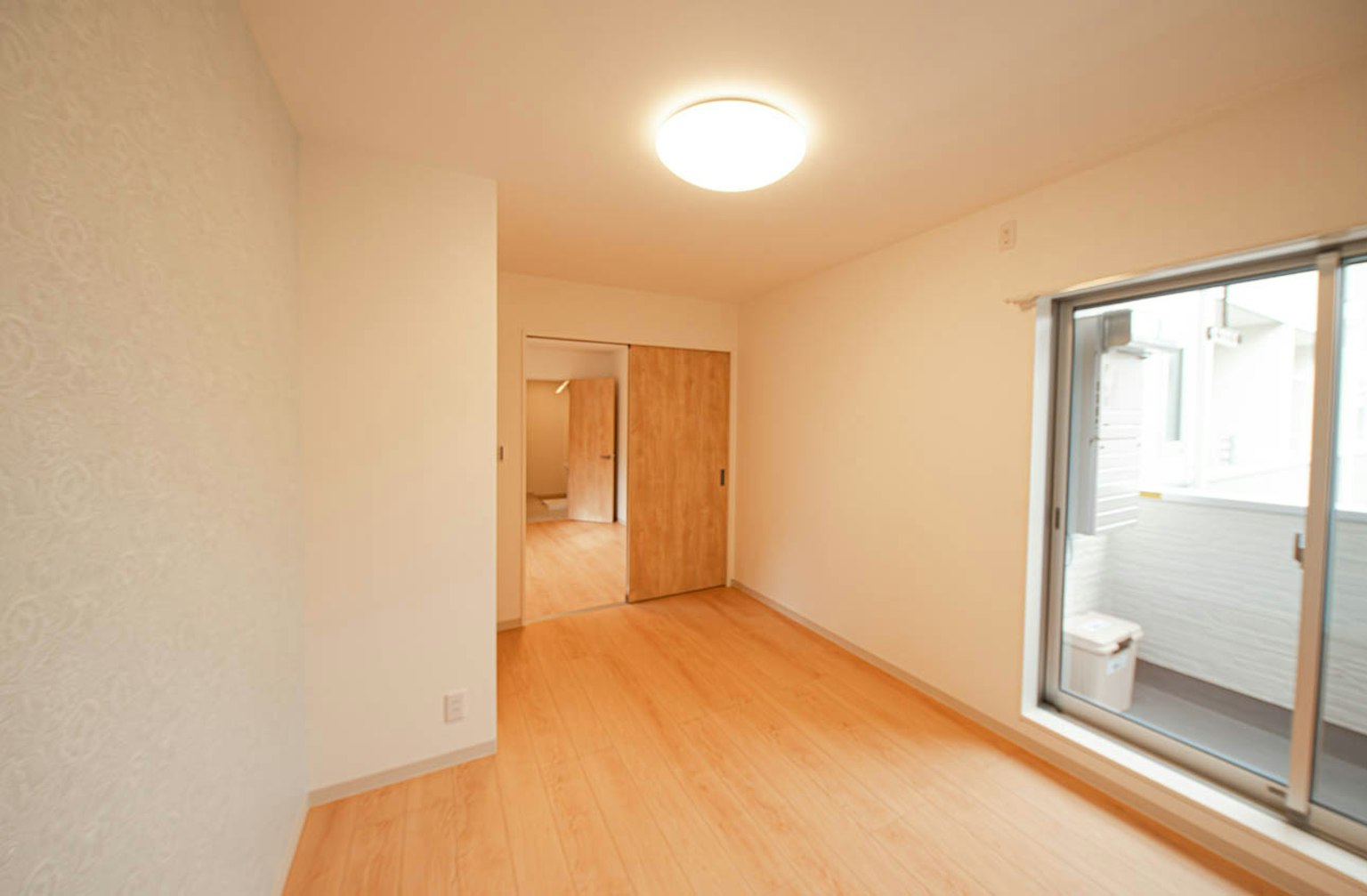 Heller Raum mit Holzboden und großem Fenster mit Türen