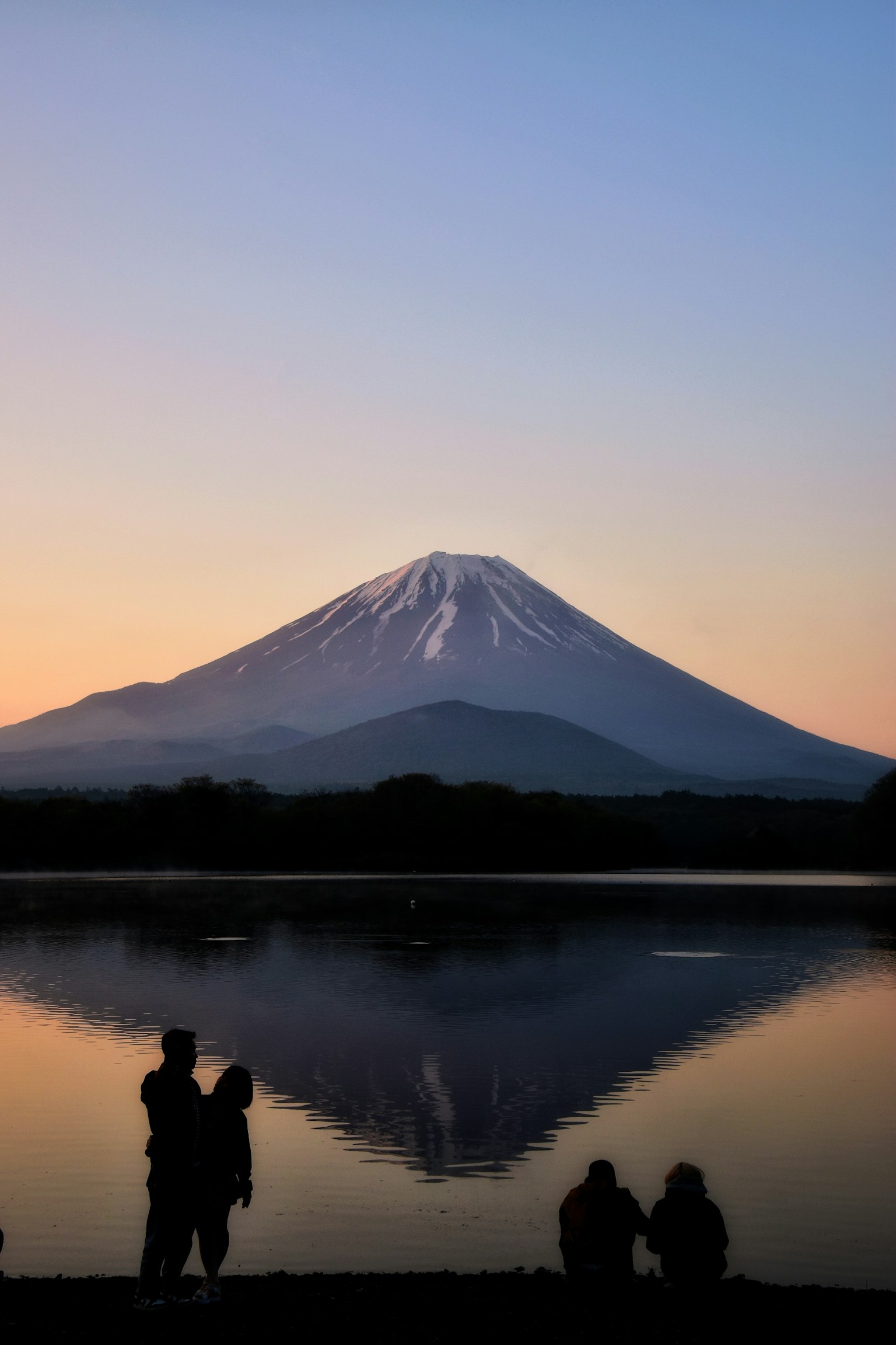 Silhouette eines Paares vor dem schönen Sonnenuntergang und dem Spiegelbild des Fuji