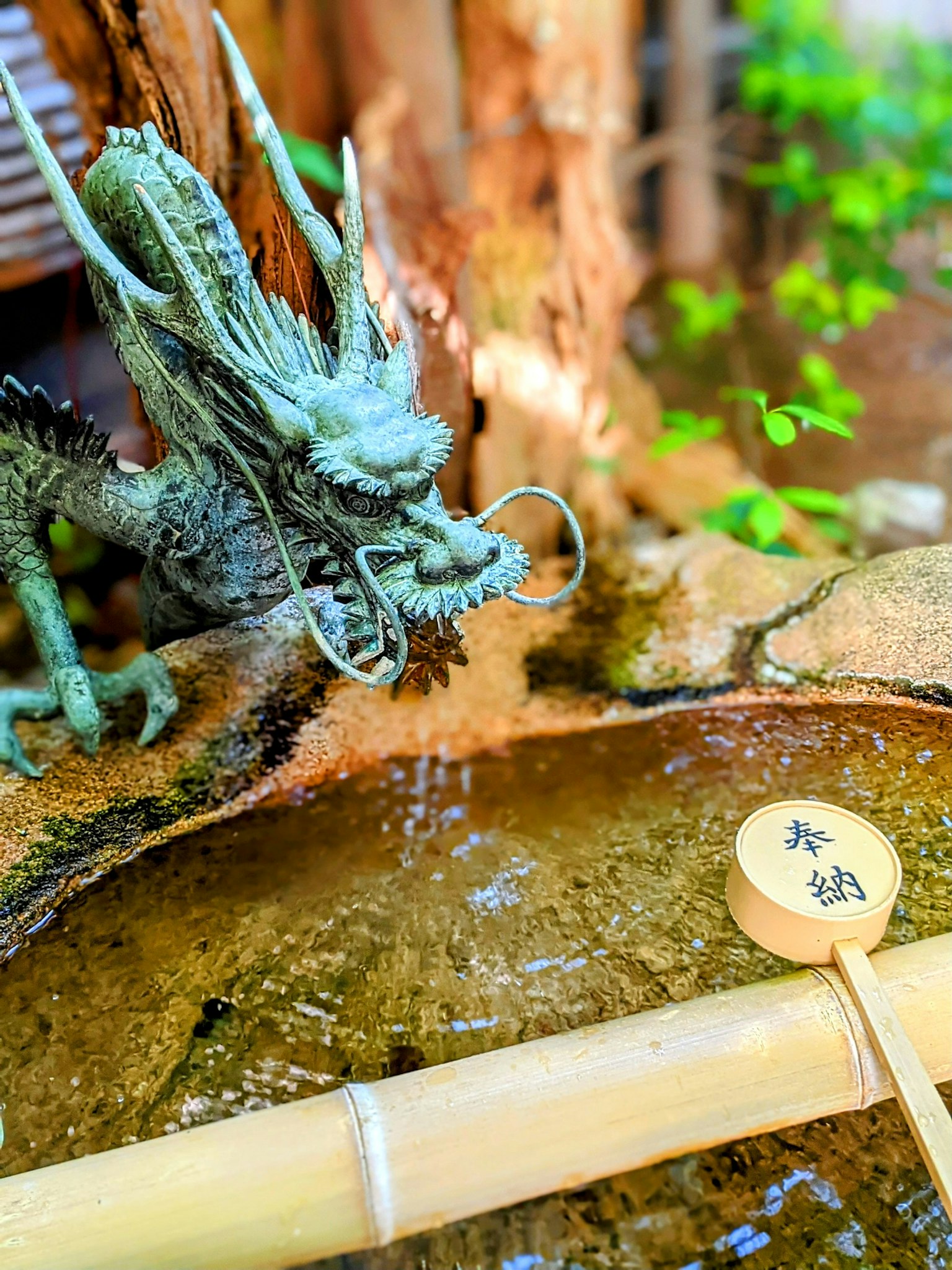 Japanese garden scene featuring a dragon sculpture and a bamboo ladle