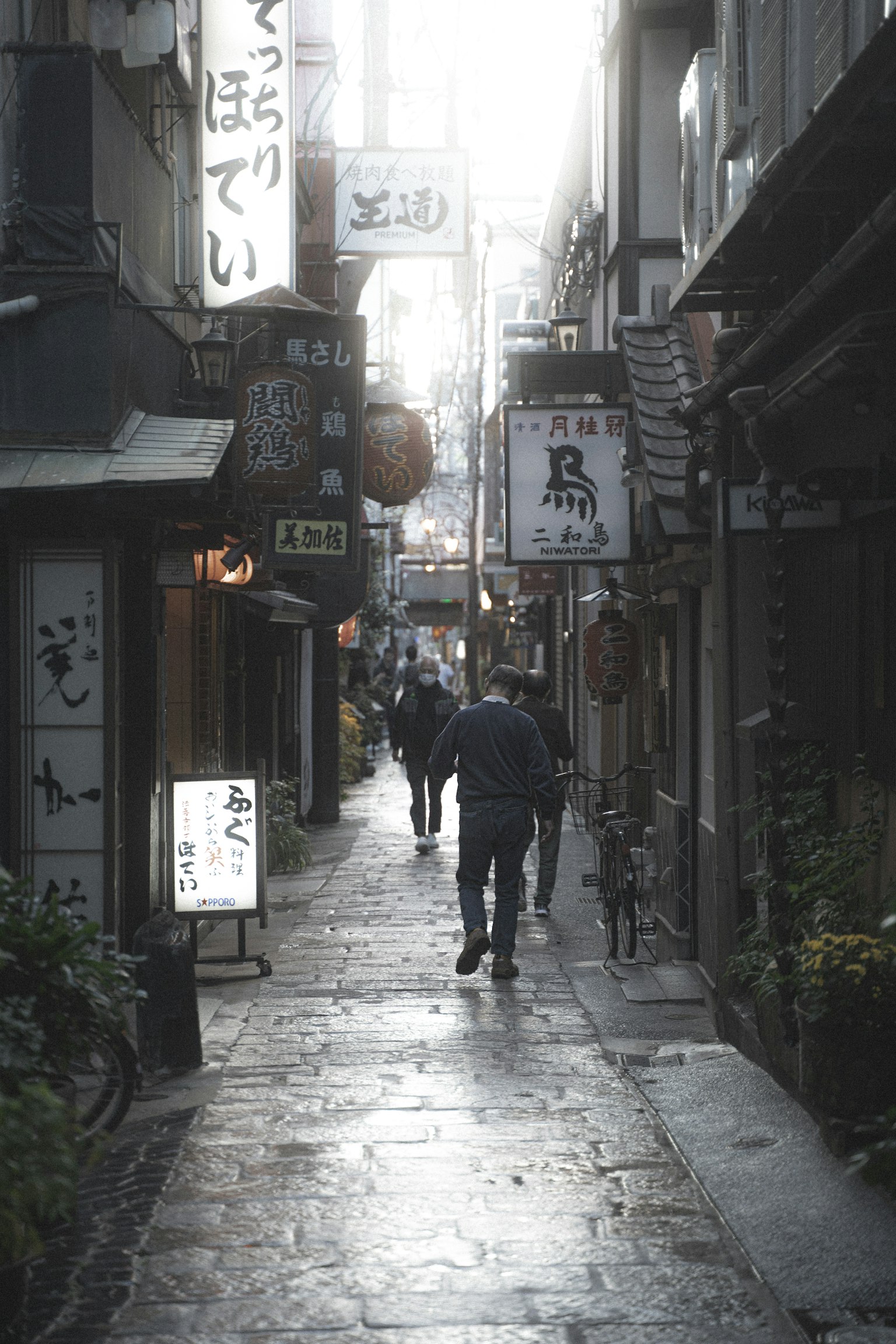 Scène du soir avec des gens marchant dans une ruelle étroite avec de nombreux panneaux