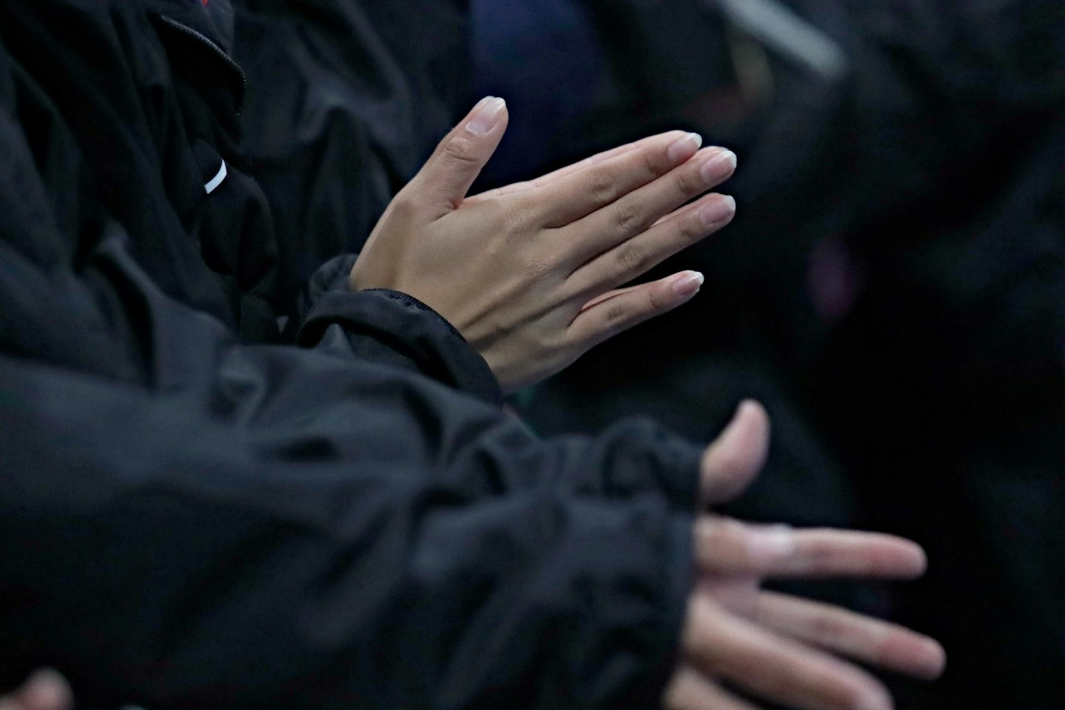 Gros plan de mains applaudissant portant des vestes noires