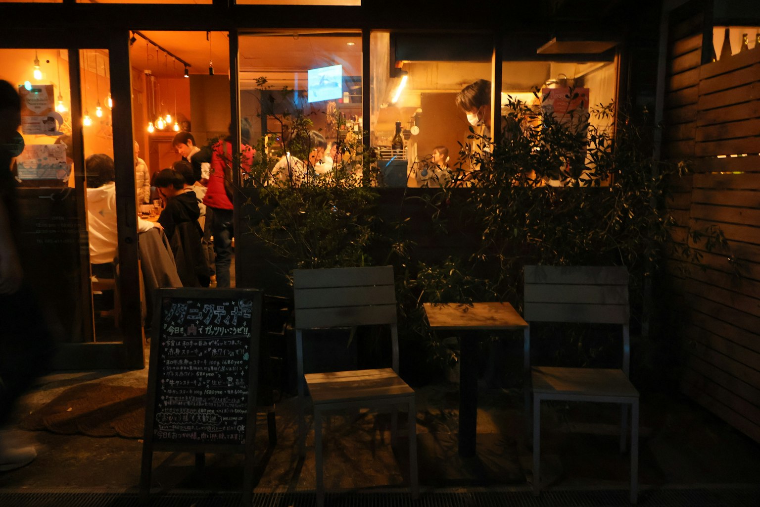 夜のカフェの外観 椅子とテーブルが並び 照明が温かい雰囲気を演出