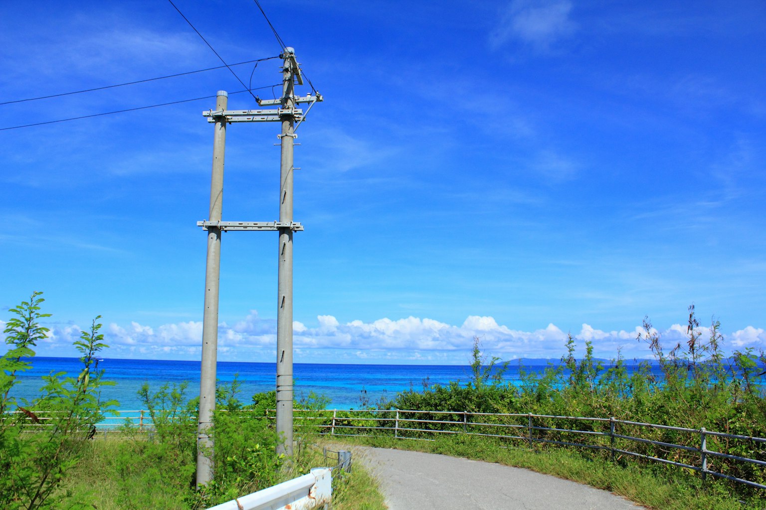 背景是蓝色海洋和天空的电线杆和道路风景