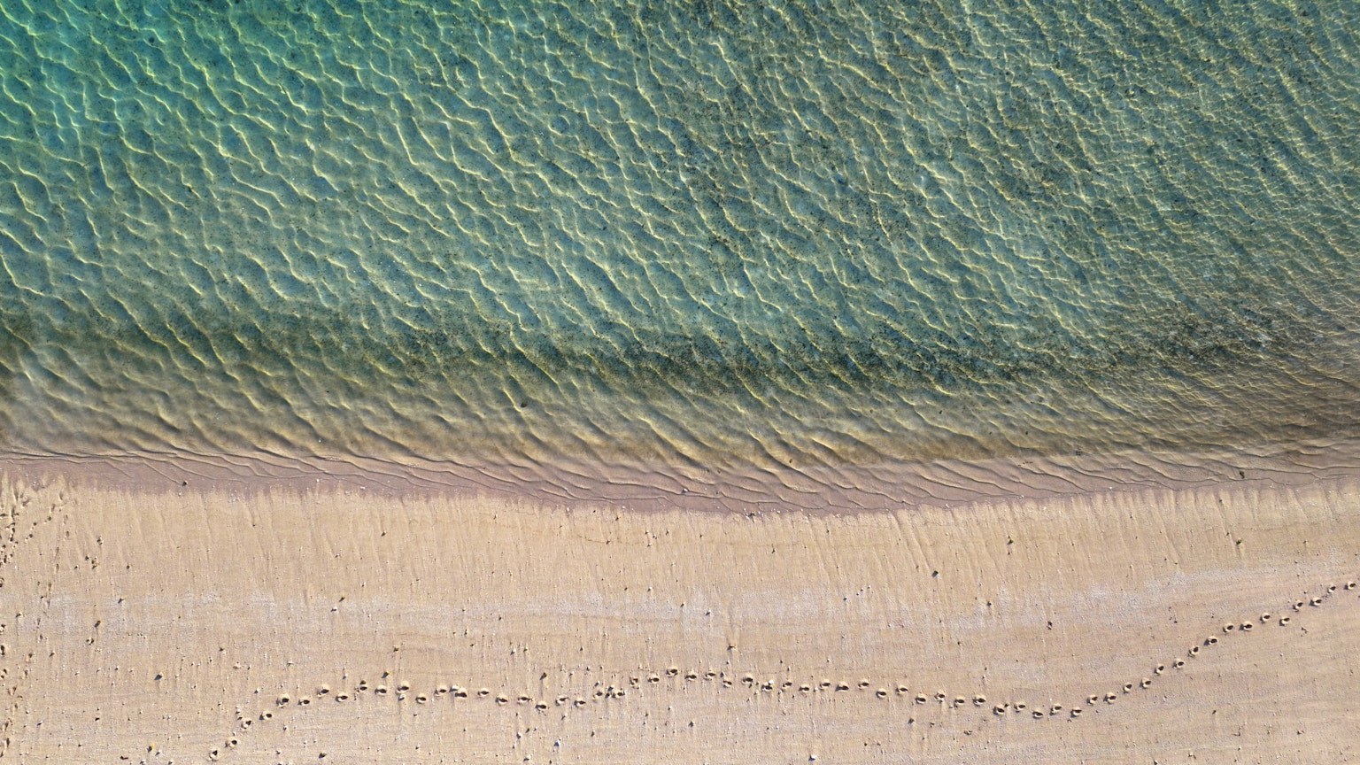 Vista aérea de agua turquesa encontrando una playa de arena