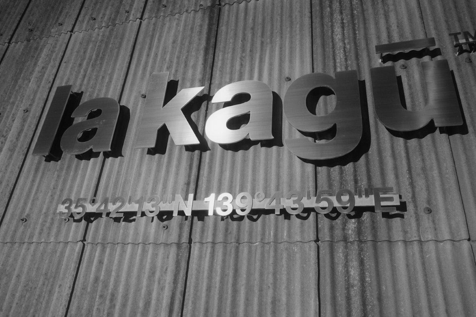 Schild mit dem Text 'la kagū', montiert an einer schwarz-weißen Wand