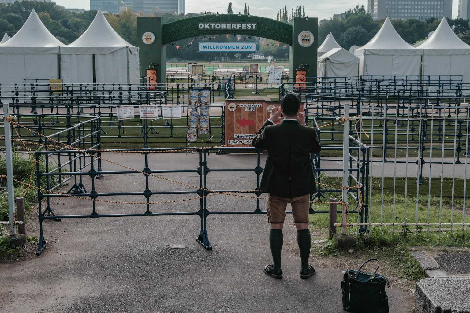 A man looking at the entrance gate with tents in the background at an event