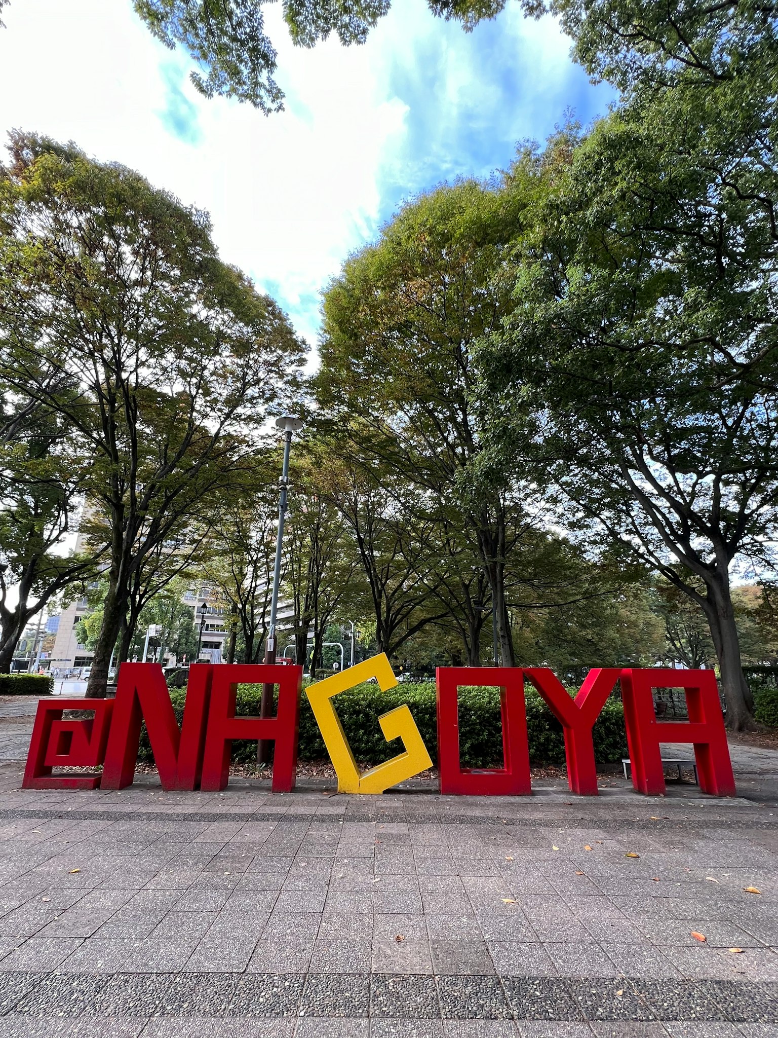 Tanda besar Nagoya di taman dikelilingi pepohonan