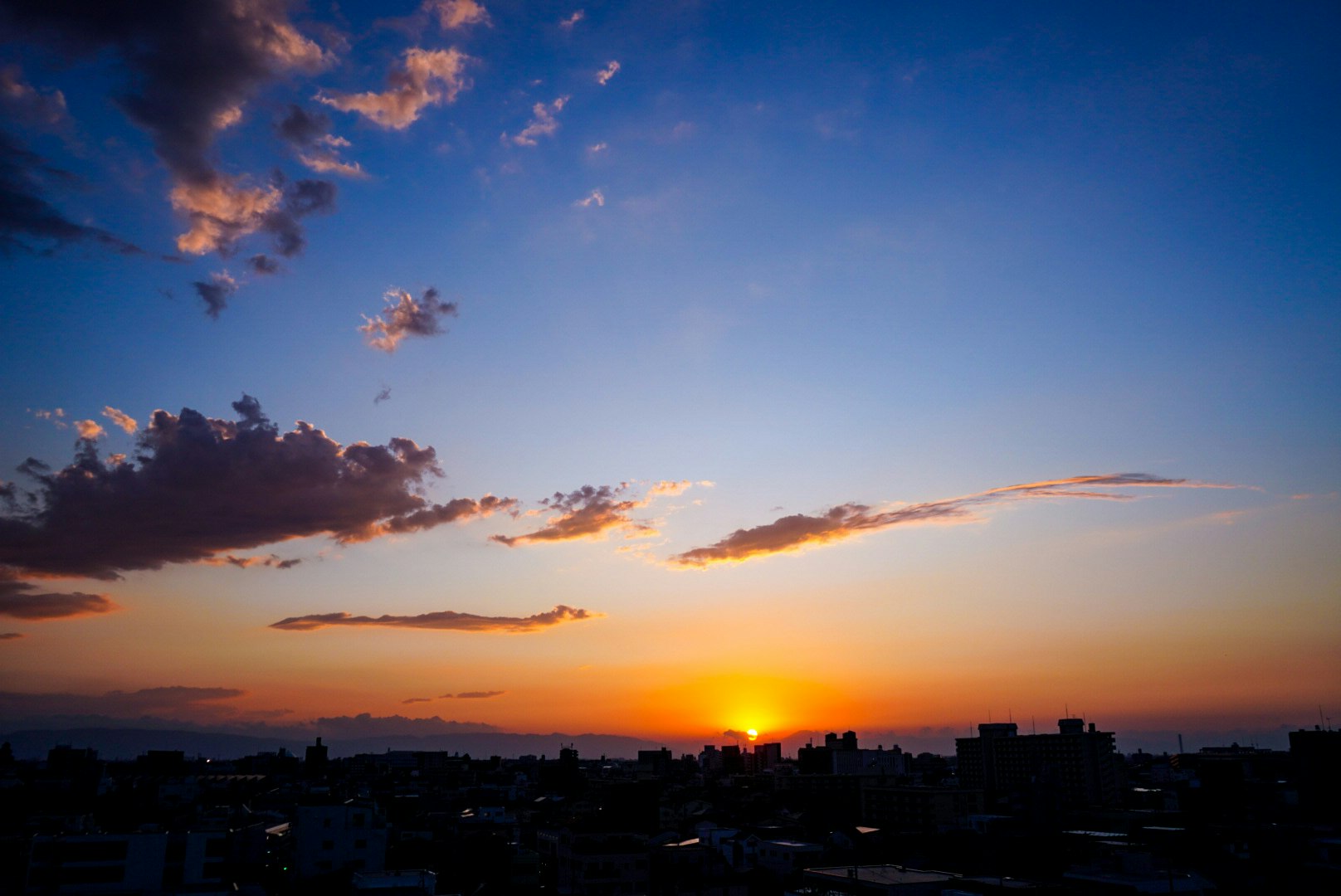 夕焼けの空と雲、街並みのシルエット